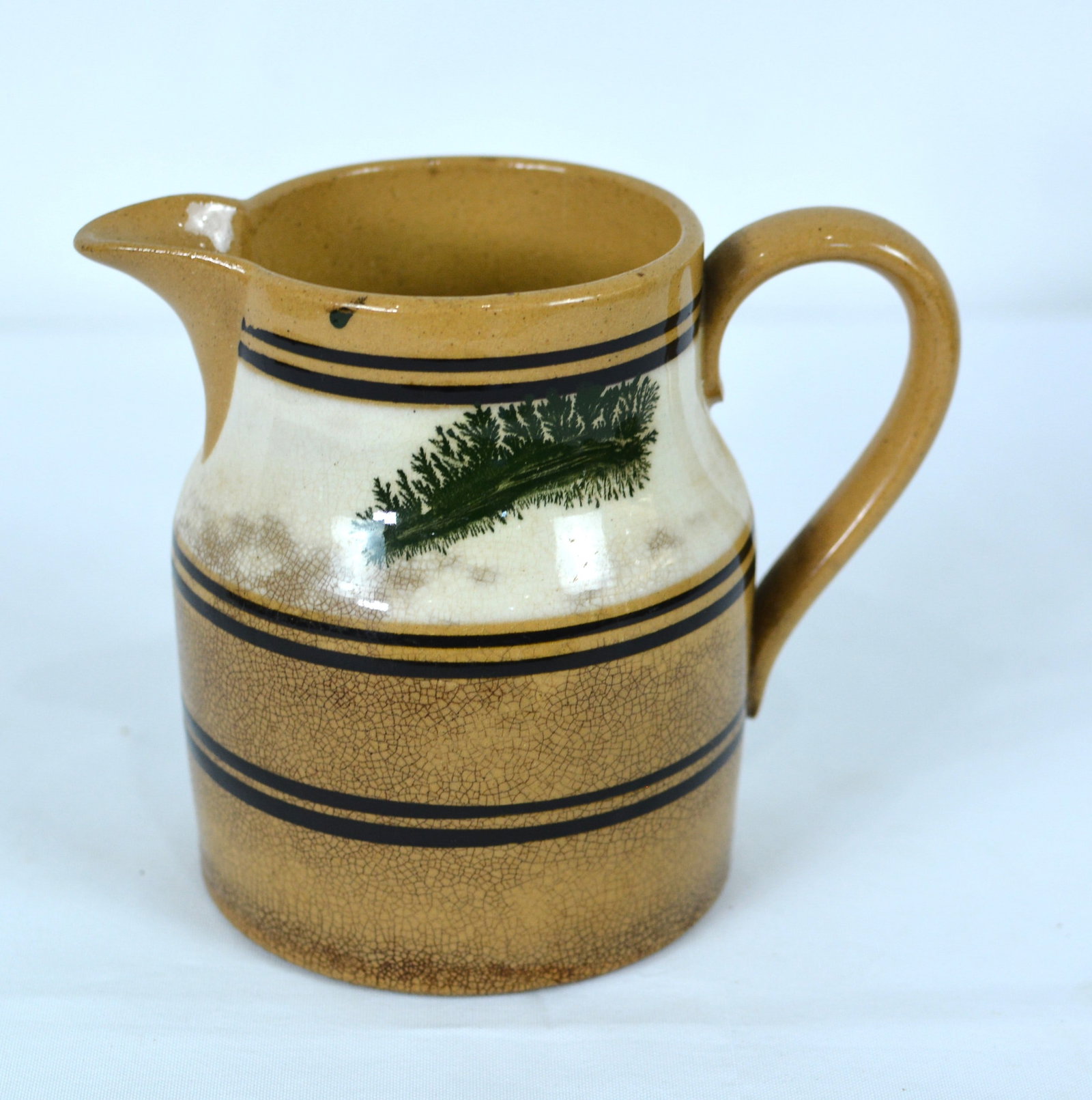 19th Century English Mochaware Cream Pitcher with Green Decoration: Early 19th-century English mochaware cream pitcher featuring striking green dendritic "seaweed" decoration on a cream-colored slip reserve. The baluster-form body is accented with multiple black