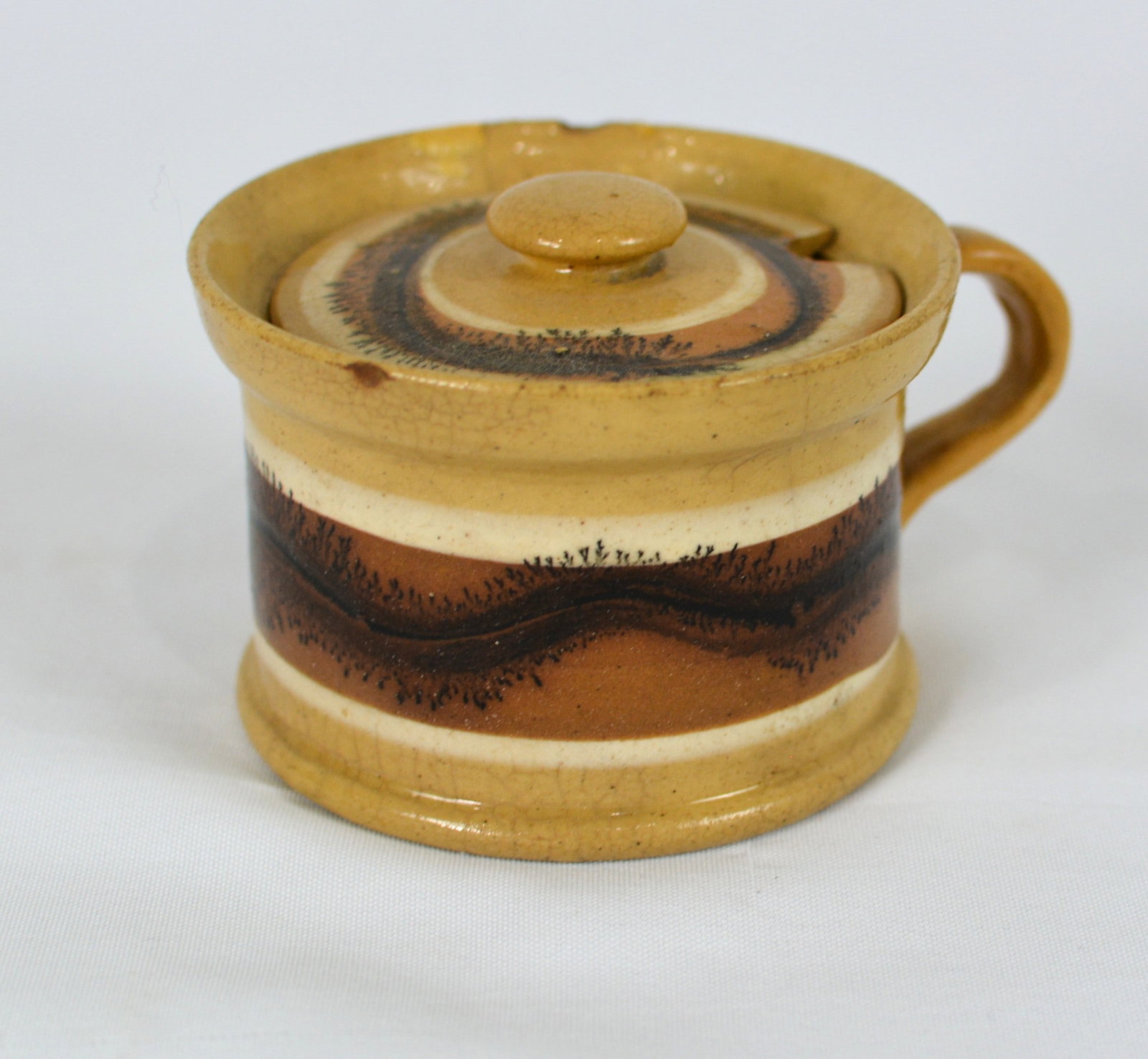 19th Century Mocha ware Covered Mustard Pot with Earthworm Decoration: Charming 19th-century English mocha ware covered mustard pot featuring classic banded slip decoration with a distinctive dark brown earthworm pattern encircling the body and lid. Fitted with a strap