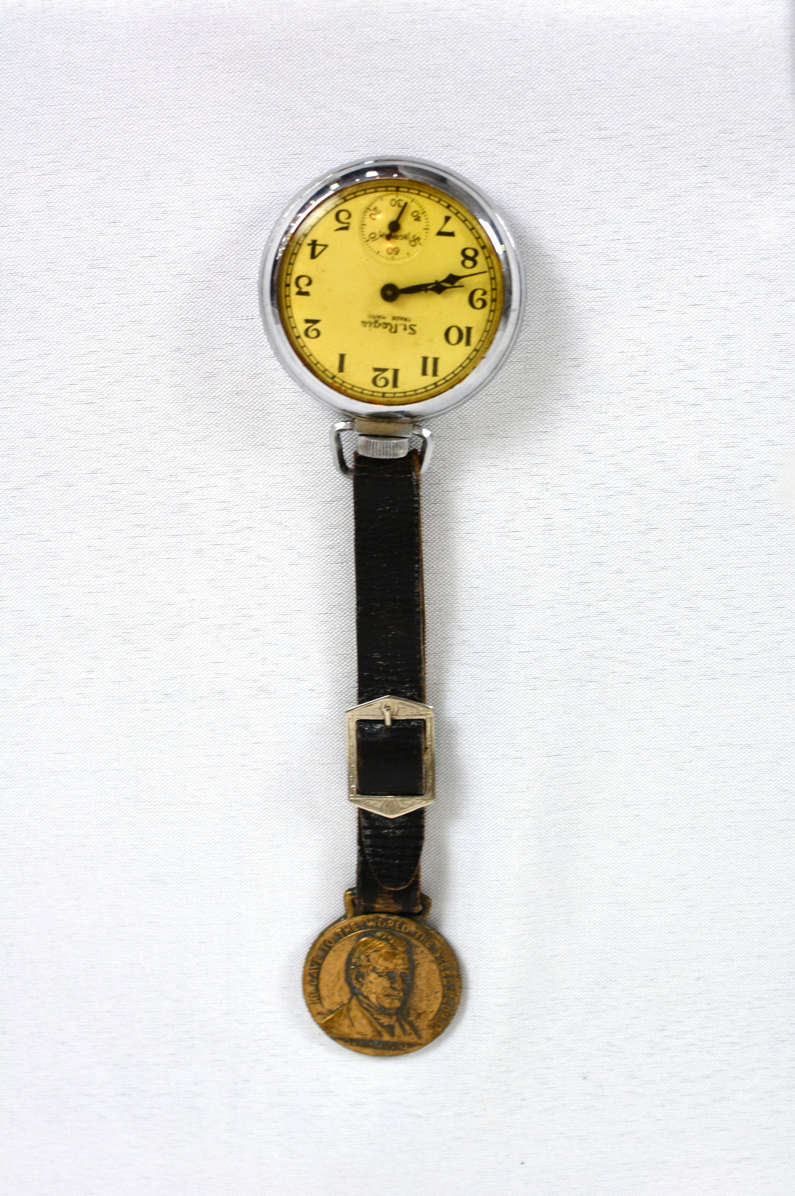 John Deere Advertising Watch Fob with “The Plow: 1937 John Deere watch on a black leather strap. “He Gave to the World the Steel Plow.” Size: Overall length approximately 8 in.; medal approximately 1 in. diameter.