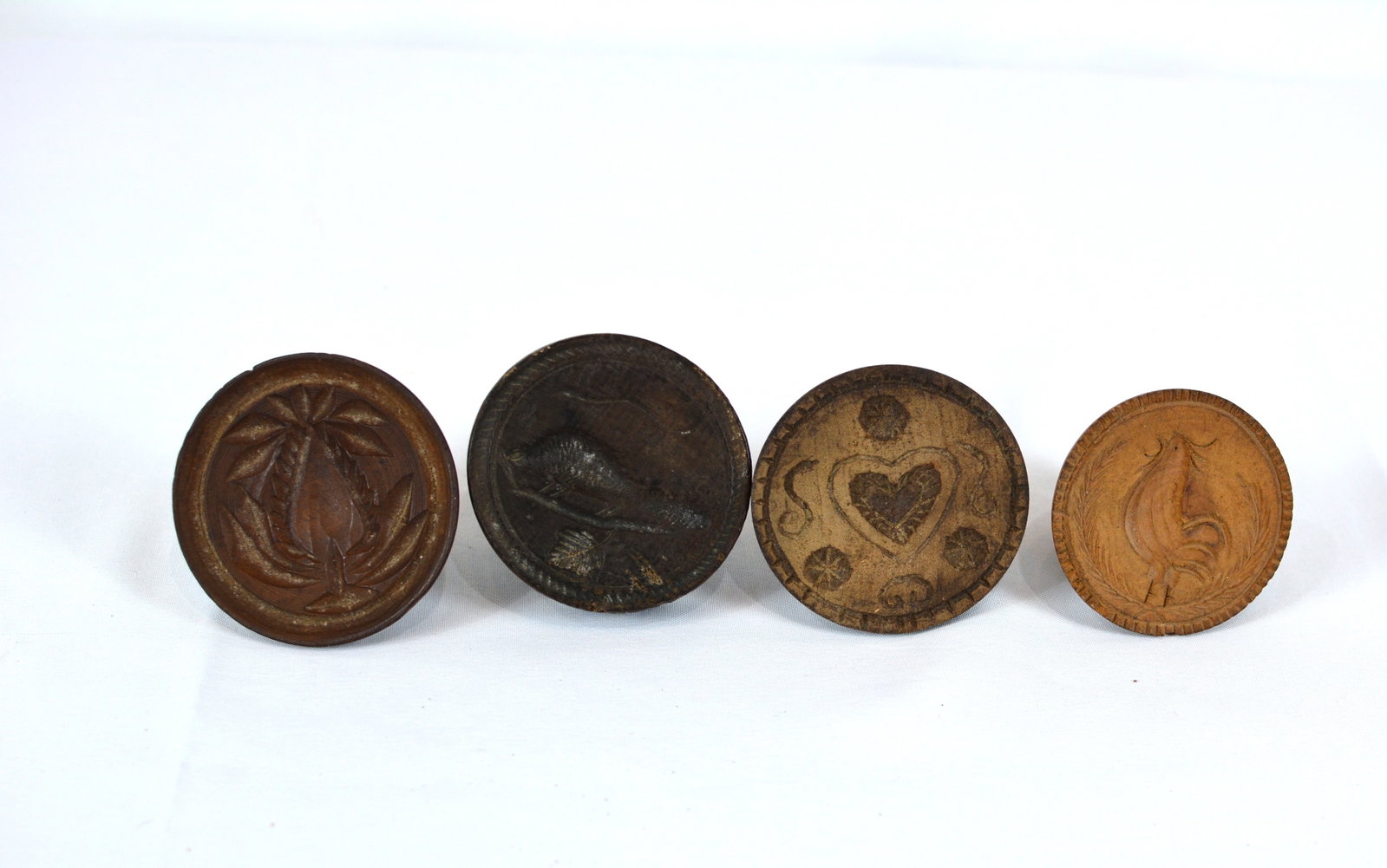 Collection of Four Early American Carved Wooden Butter Prints: Charming collection of four early American carved wooden butter prints, tulip, squirrel, heart, and rooster. 3 inches D X 3 inches T.