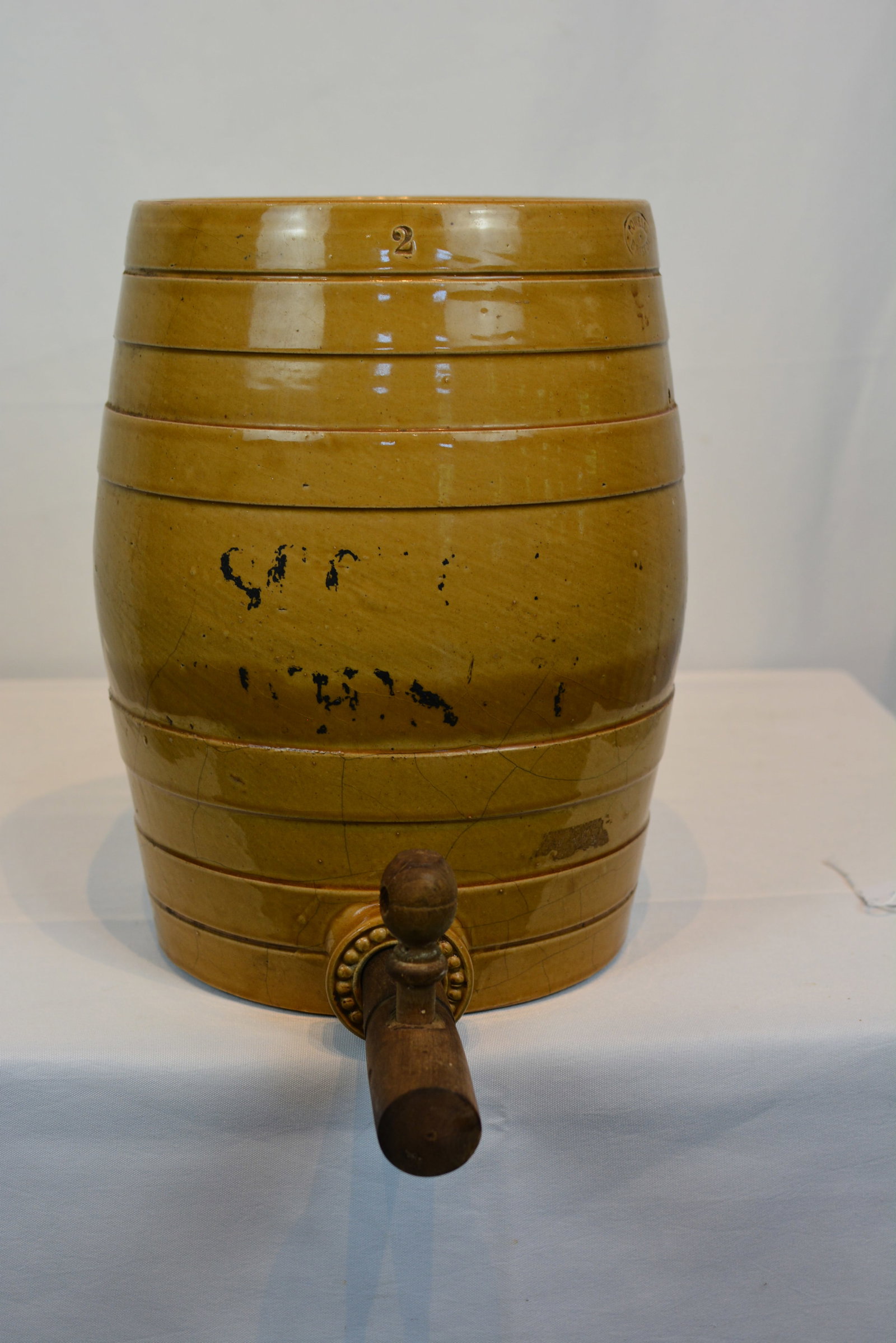Yellowware Water Cooler with Wooden Spigot Handle: Yellowware water cooler featuring a barrel-form body with molded band decoration and a rich honey-yellow glaze. The cooler retains its original-style wooden spigot handle and decorative ceramic spout