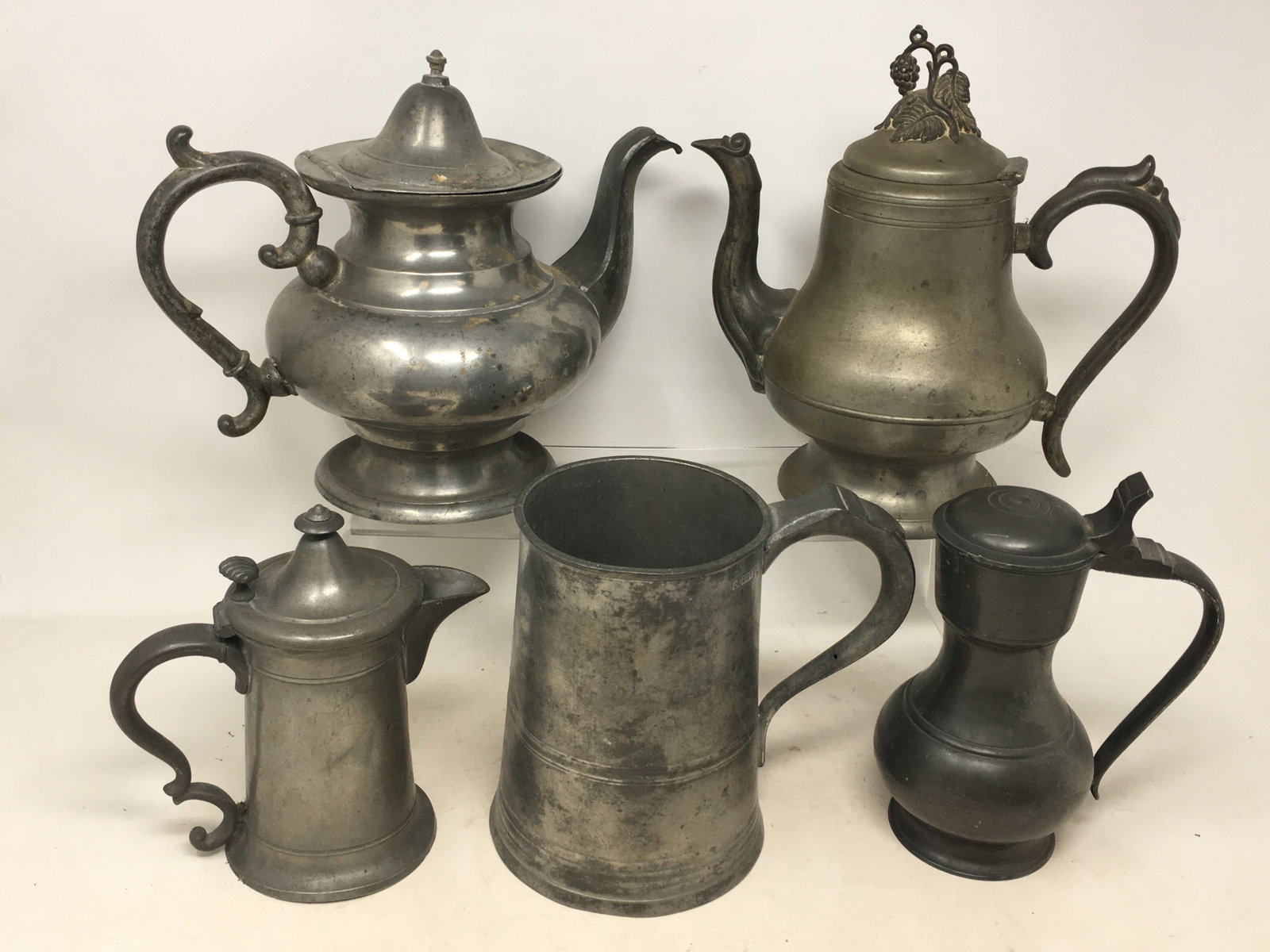 Group of Pewter Items: Group of Pewter Items. Incl. a 1-quart measure, 3 spouted, hinged lidded teapots/coffeepots, and a lidded syrup dispenser. Tallest with grapes and leaves finial, 8.5"H.