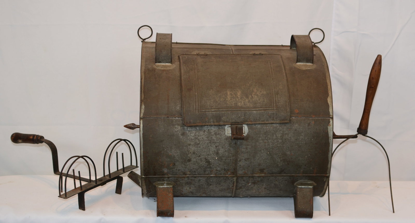 Fireplace Hand-Cranked Tin Roaster: Early fireplace hand-cranked tin roaster featuring a cylindrical rotating body, hinged access door, 20 in. W x 12 in. D x 16 in. H.