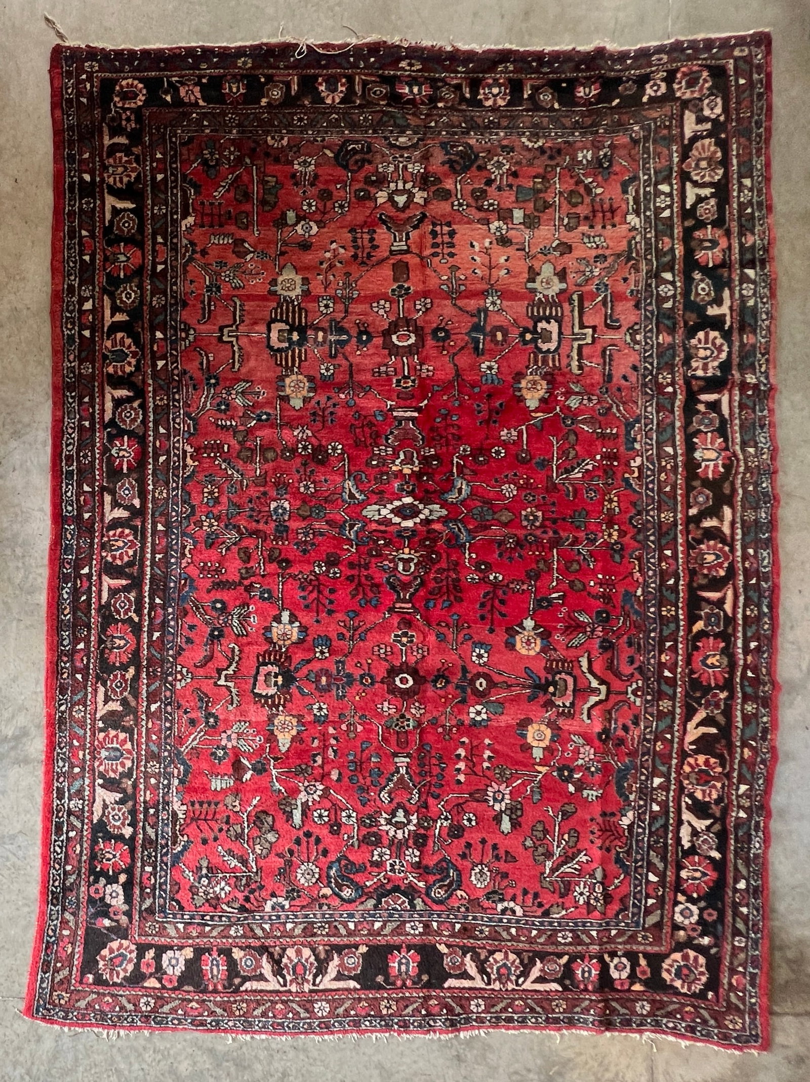 Antique Hand-Knotted Persian Heriz Area Rug with Floral Medallion Design: Antique hand-knotted Persian Heriz-style area rug featuring a richly colored red field adorned with an intricate allover floral and vine pattern centered around a geometric medallion. The rug is frame