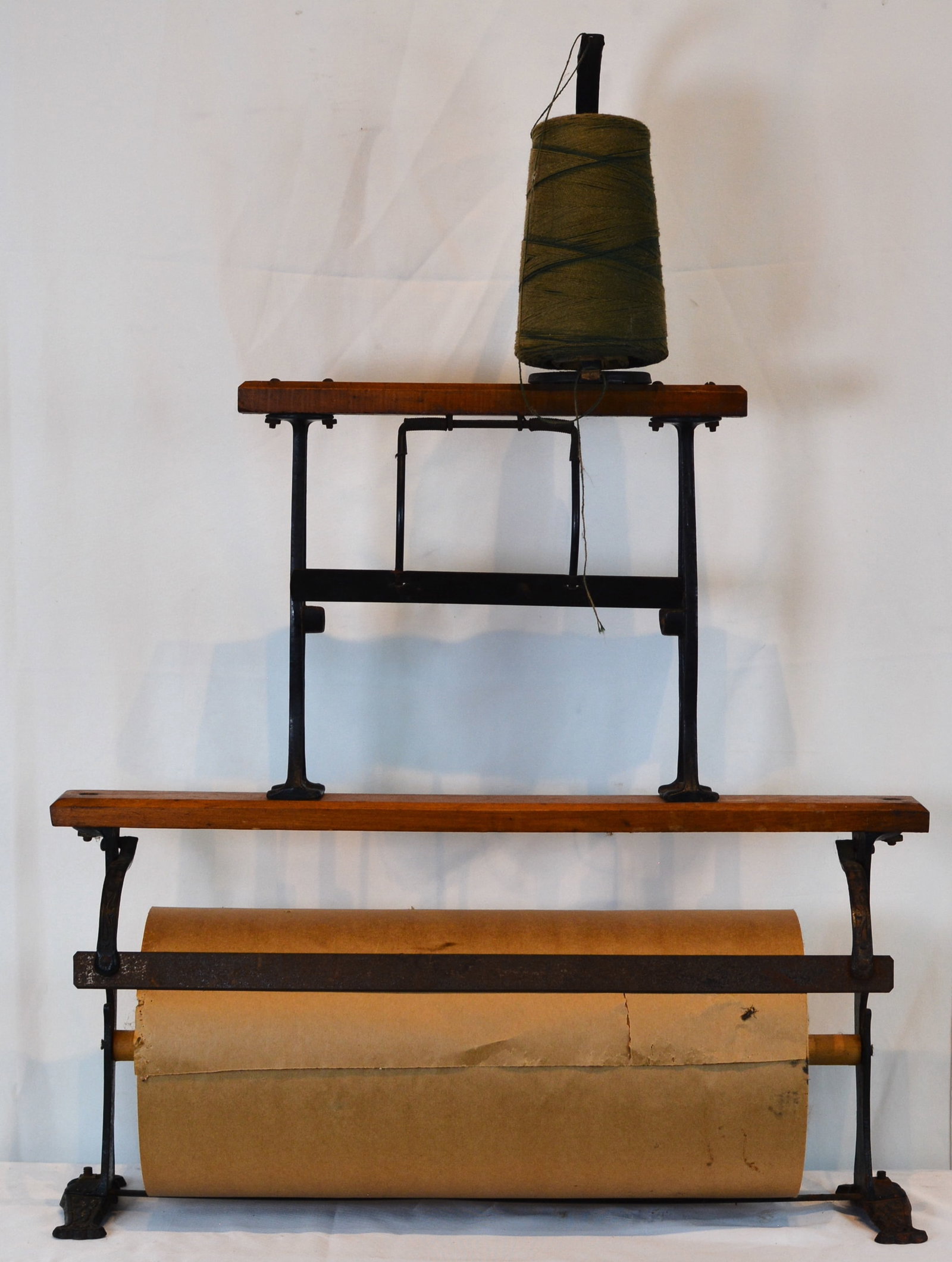 General Store Wrapping Paper & String Dispenser Stand with Cast Iron Frame: General store wrapping station featuring a cast iron and wood dispenser stand fitted with a large roll of brown kraft wrapping paper and spool of packing twine. 24" W x 19" D x 33" H.