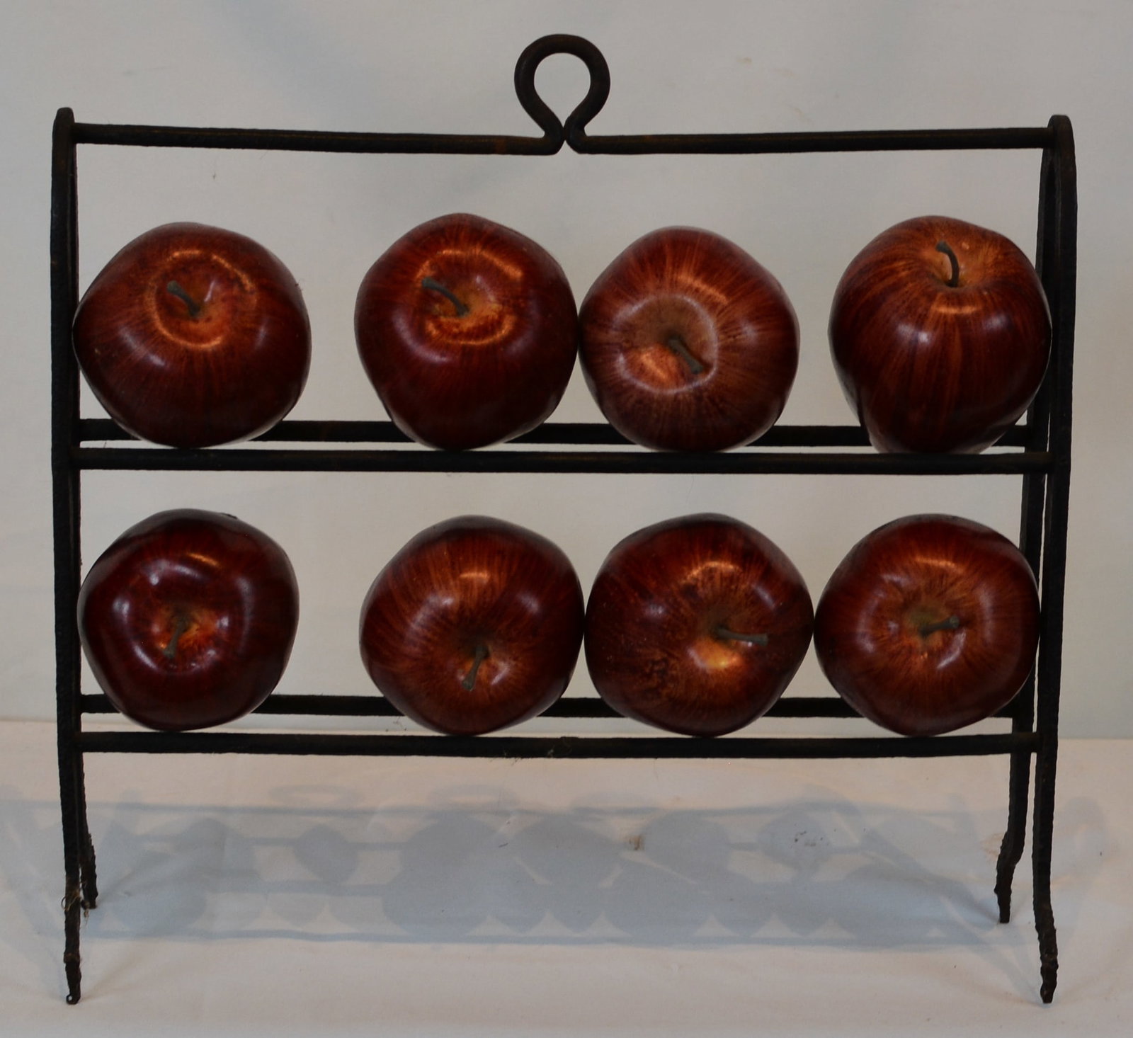 Cast Iron Apple Rack with Eight Wooden Apples: Wrought iron apple roasting rack ,with a decorative loop handle at the crest and shaped feet. 14" W x 4" D x 12" H.