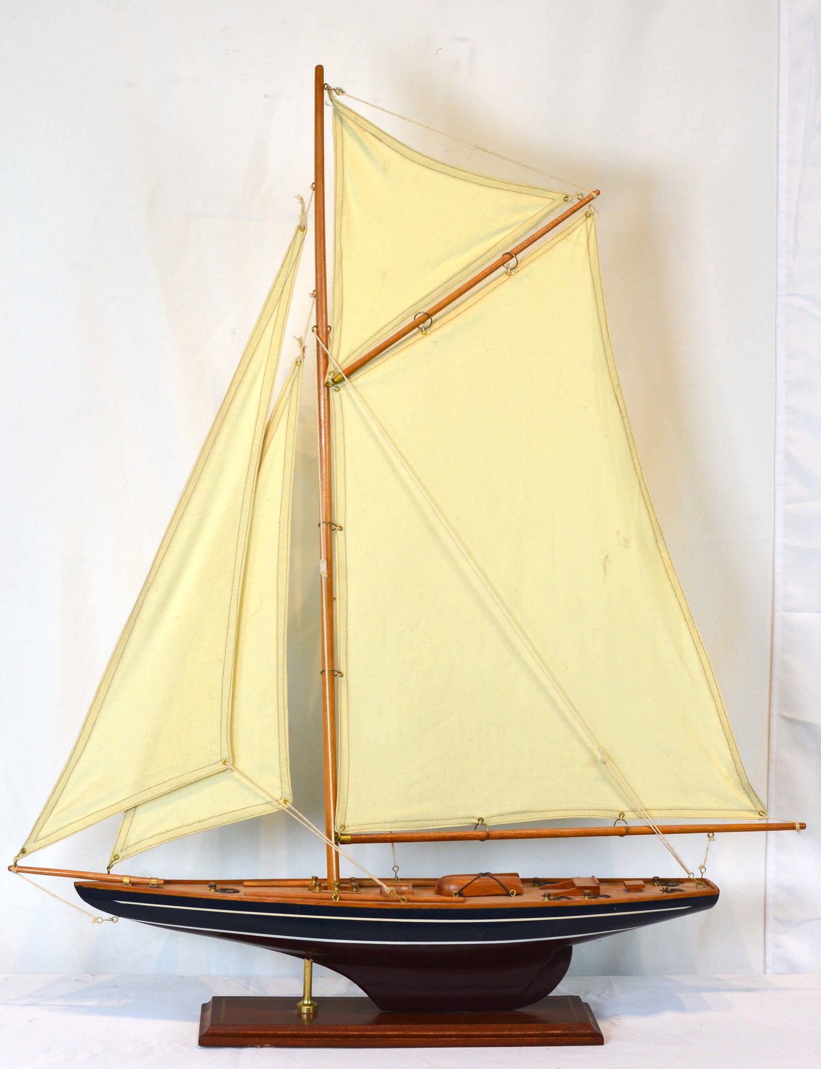 Large Handcrafted Wooden Sailboat Model with Cloth Sails on Mahogany Base: Handcrafted sailing vessel model featuring a single-mast rig with multiple cloth sails, detailed deck fittings, brass hardware, and a finely finished wooden hull. Mounted on a polished mahogany-style