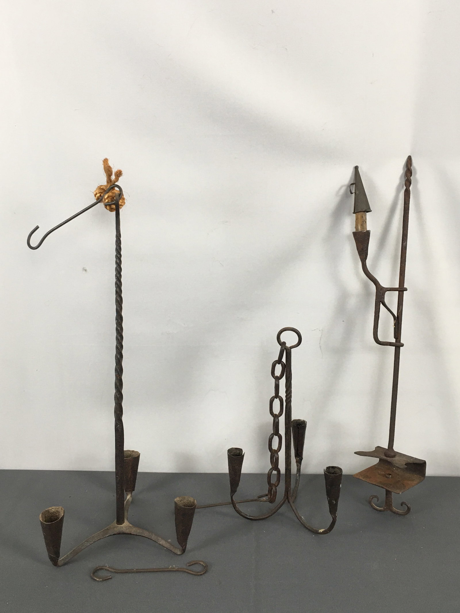 Early Wrought Iron Lighting: Early Wrought Iron Lighting. (2) hanging 3-candleabras with twist stems, and a tabletop clamp-on candle holder with twist end and snuffer. Tallest 21"H