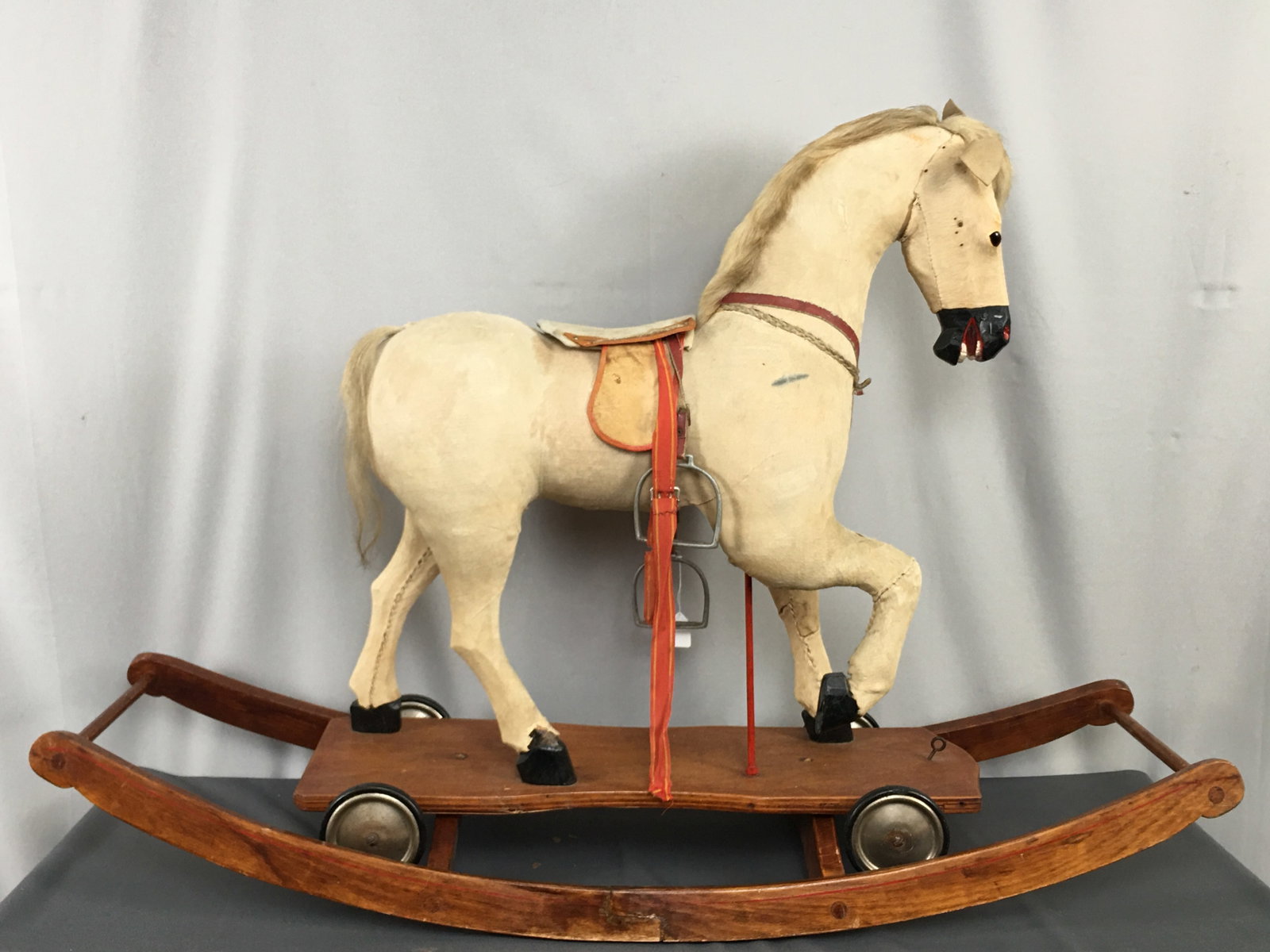 Straw Stuffed Rocking Horse: Straw Stuffed Rocking/Rolling Horse. Wooden legs & head with hide covered, straw filled body. On wooden stand with metal wheels and removable rockers. Includeds saddle & stirrups. Some damage to hide
