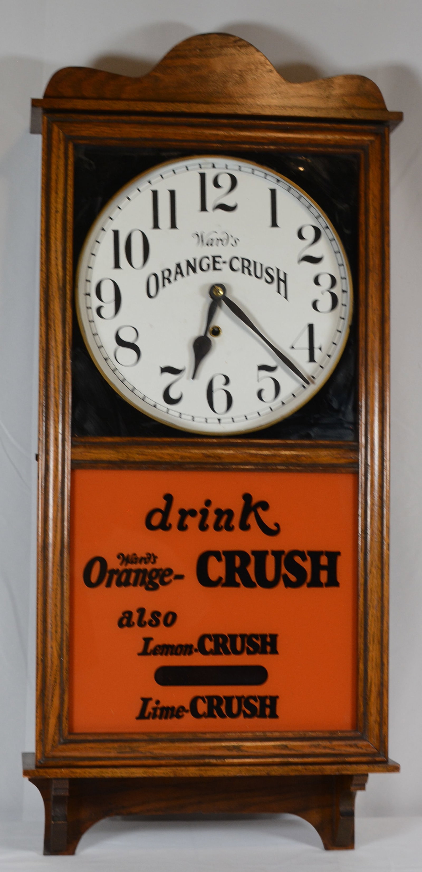 Early Ward's Orange-Crush Advertising Clock: Early Ward's Orange-Crush advertising wall clock housed in a substantial oak case with decorative crest and large porcelain-style clock dial lettered "Ward?s Orange-Crush." The lower illuminated