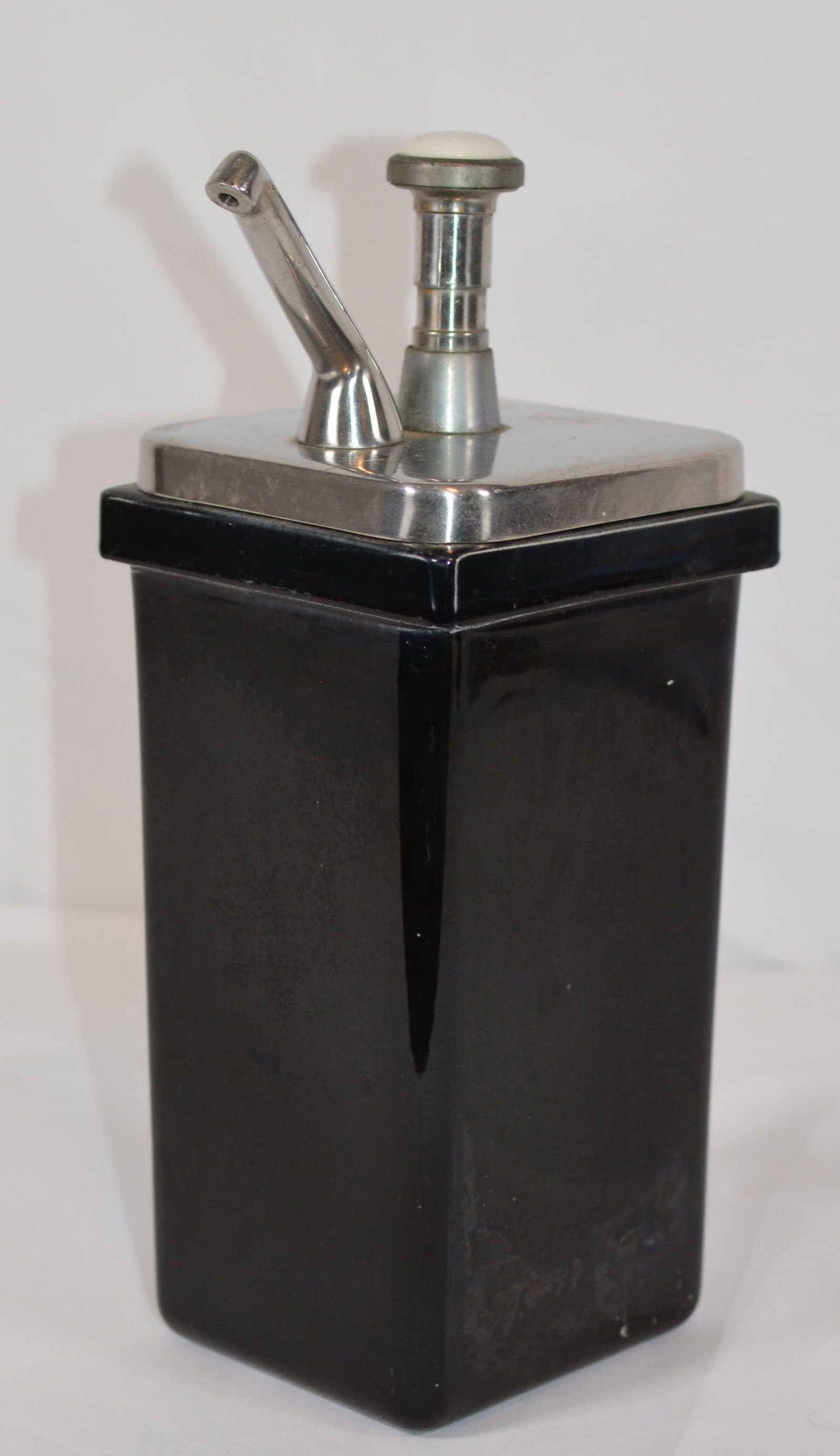 Vintage Cherry Soda Fountain Syrup Dispenser: Vintage Cherry soda fountain syrup dispenser featuring a tall rectangular black ceramic body with chrome-plated metal top, pump, and dispensing spout. Designed for countertop use at an early