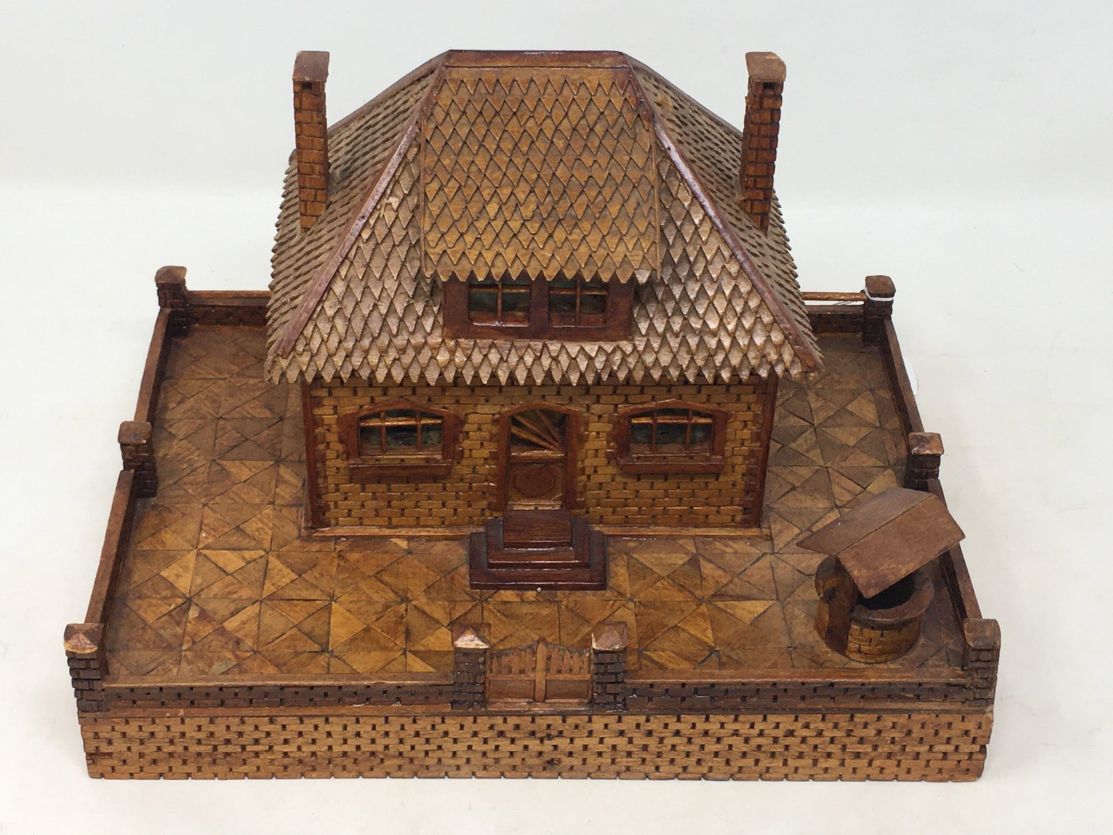 Tramp Art Carved Cottage Bank: Tramp Art Carved Cottage Bank. Made of wood with cardboard bottom with slot at back for coins. Cellophane at windows. 10.25"W x 7.25"D x 6.75"H.