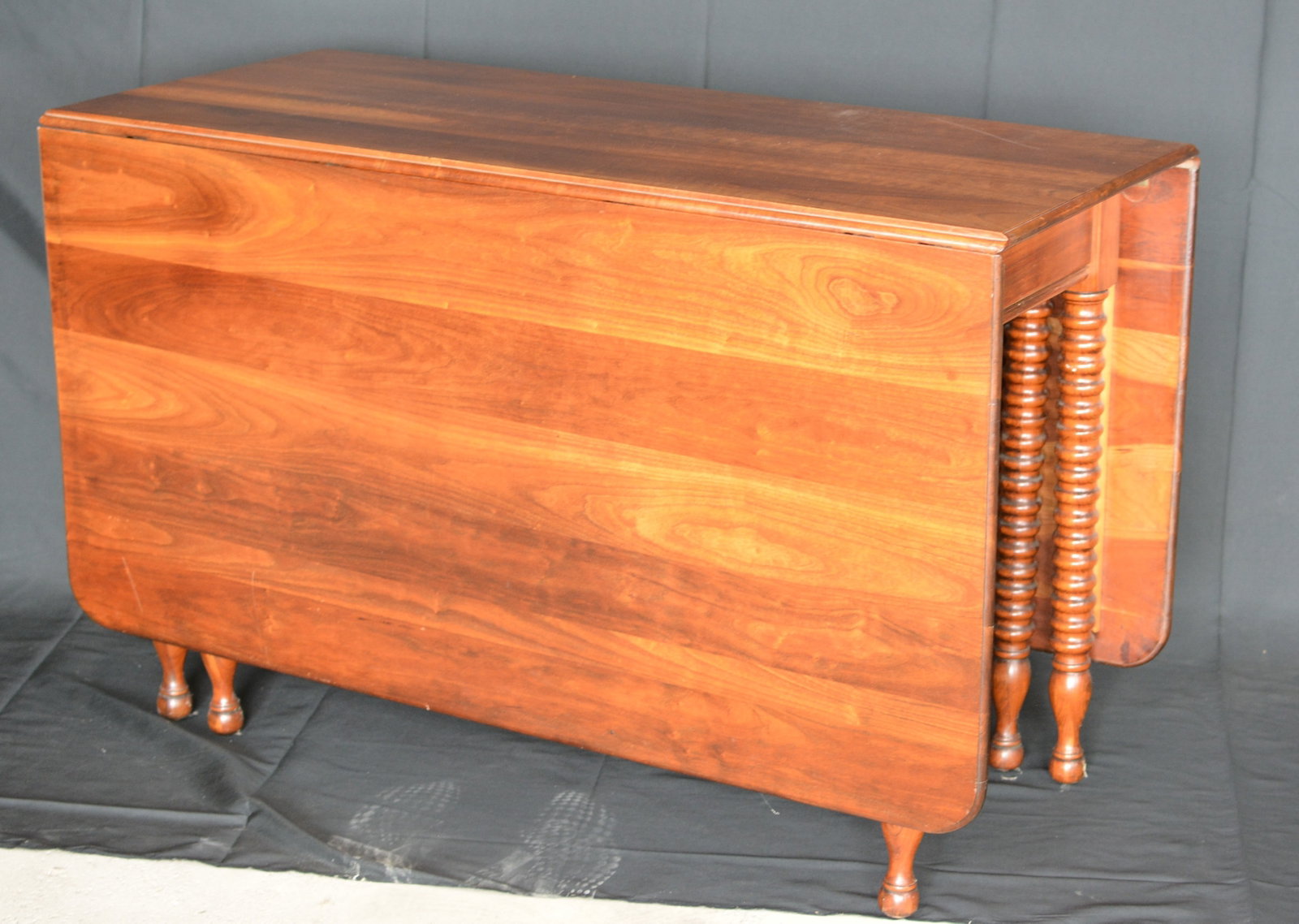 American Cherry Drop-Leaf Dining Table: American cherry drop-leaf dining table featuring a rectangular center section with two large hinged leaves allowing the table to be compactly stored or opened for dining. Supported by turned and