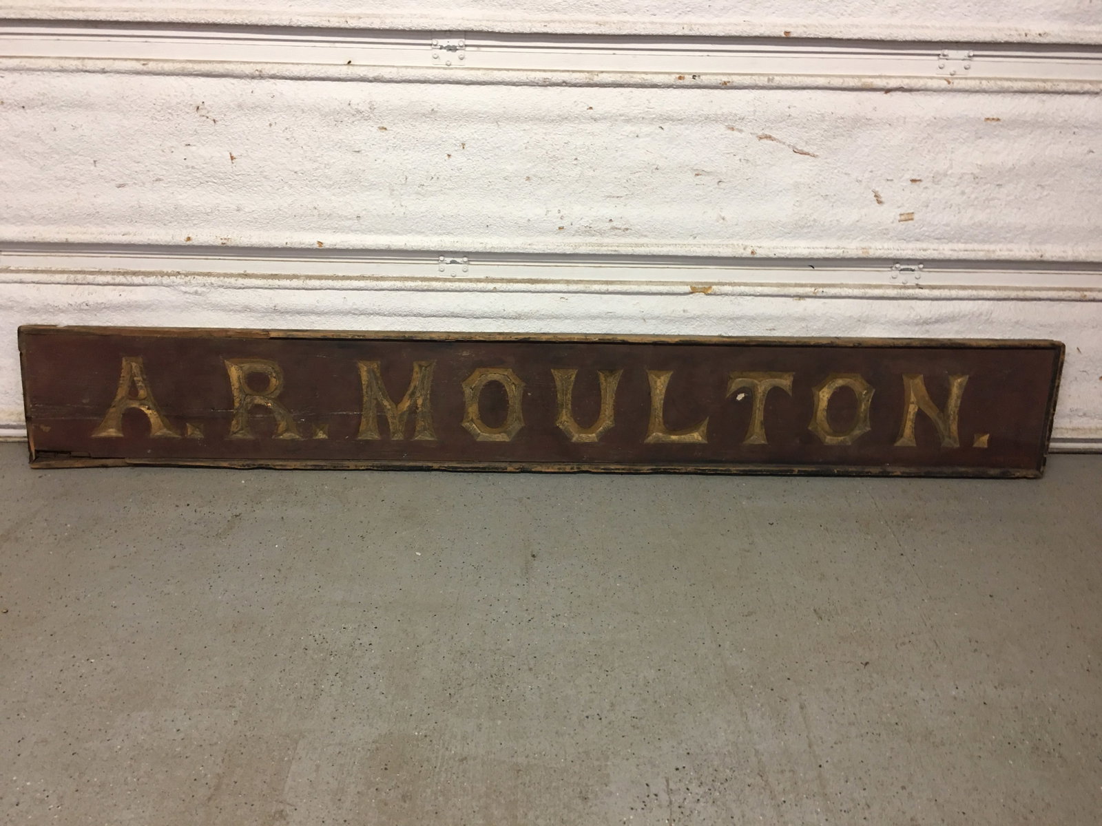 Wooden Sign, A. R. Moulton: Wooden Sign, "A. R. Moulton." in gilt letters on red background, edged in black. Square nail construction. Some loss to outer edge pieces. 108"L x 14.5"H x 2.5"D