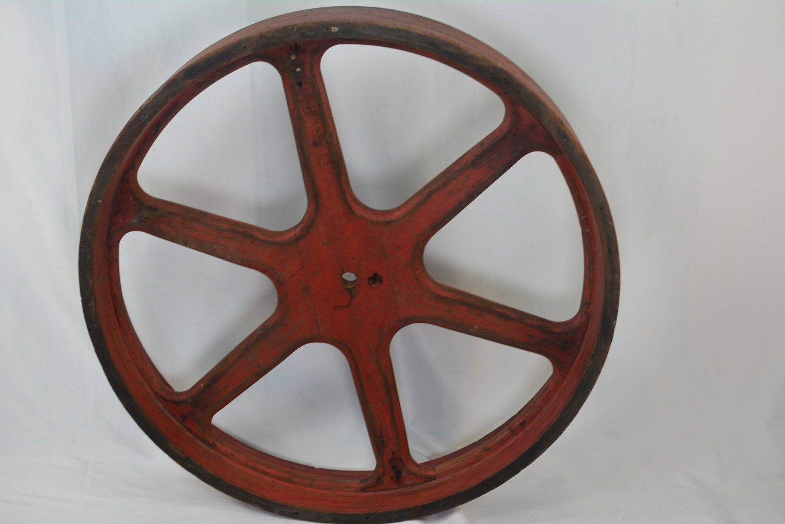 Wooden Industrial Flat-Belt Pulley ? Philadelphia, Indianapolis, & Chicago: Large antique wooden industrial flat-belt drive pulley with six-spoke construction and remnants of its original red-painted finish. Factory markings include PHILA, CHICAGO, and D.P. 4238, along with