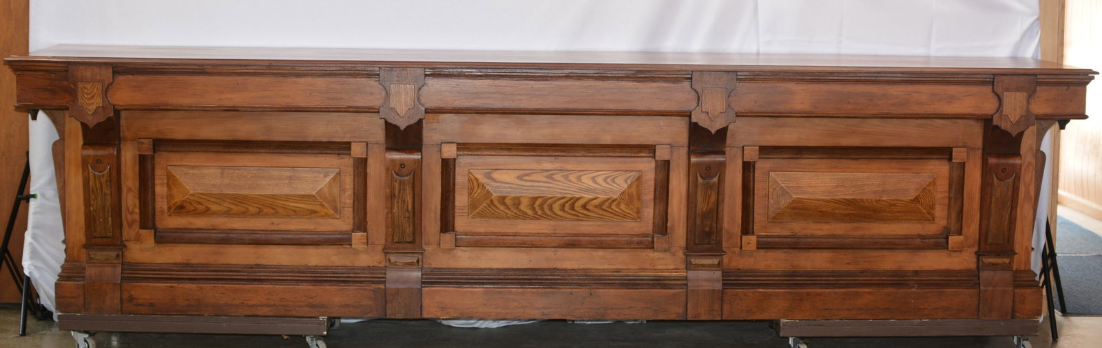 12-Foot Antique General Store Counter with Paneled Front: Impressive late 19th to early 20th century general store counter measuring approximately 12 feet long, constructed in mixed woods with a highly architectural paneled facade. The front features three