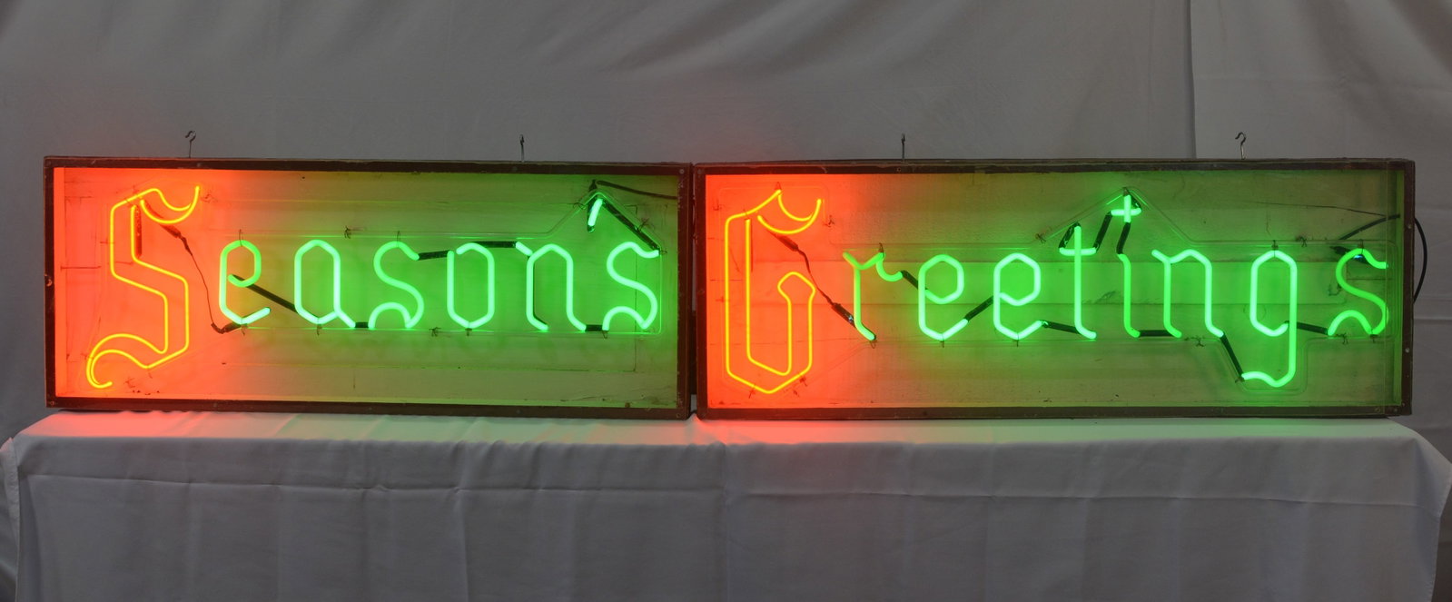 Vintage "Seasons Greetings" Two-Piece Neon Sign: Large vintage "Seasons Greetings" neon advertising/display sign, constructed in two separate framed sections. Features bright red/orange illuminated decorative initial letters with green neon script