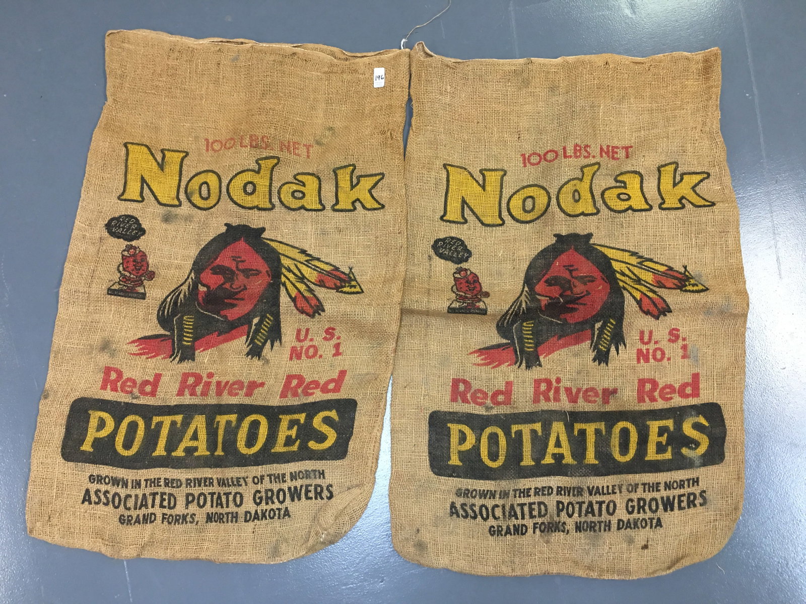 Nodak Red River Potato Sacks: Nodak Red River Potato Sacks. Two burlap sacks from Associated Potato Growers, Grand Forks, North Dakota, featuring an American Indian brave. Approx. 23" x 35.5"