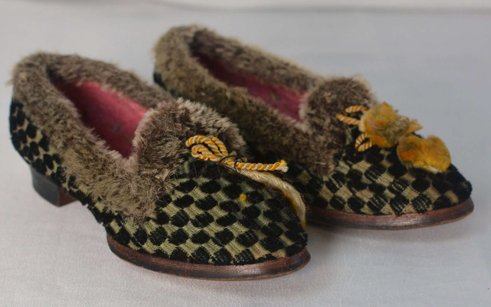 19th Century Child's Velvet & Fur-Trimmed Shoes: Charming pair of antique child's shoes, likely late 19th century, fashioned in patterned green and black velvet with fur-trimmed openings and red interiors. Each features decorative cord and pom-pom