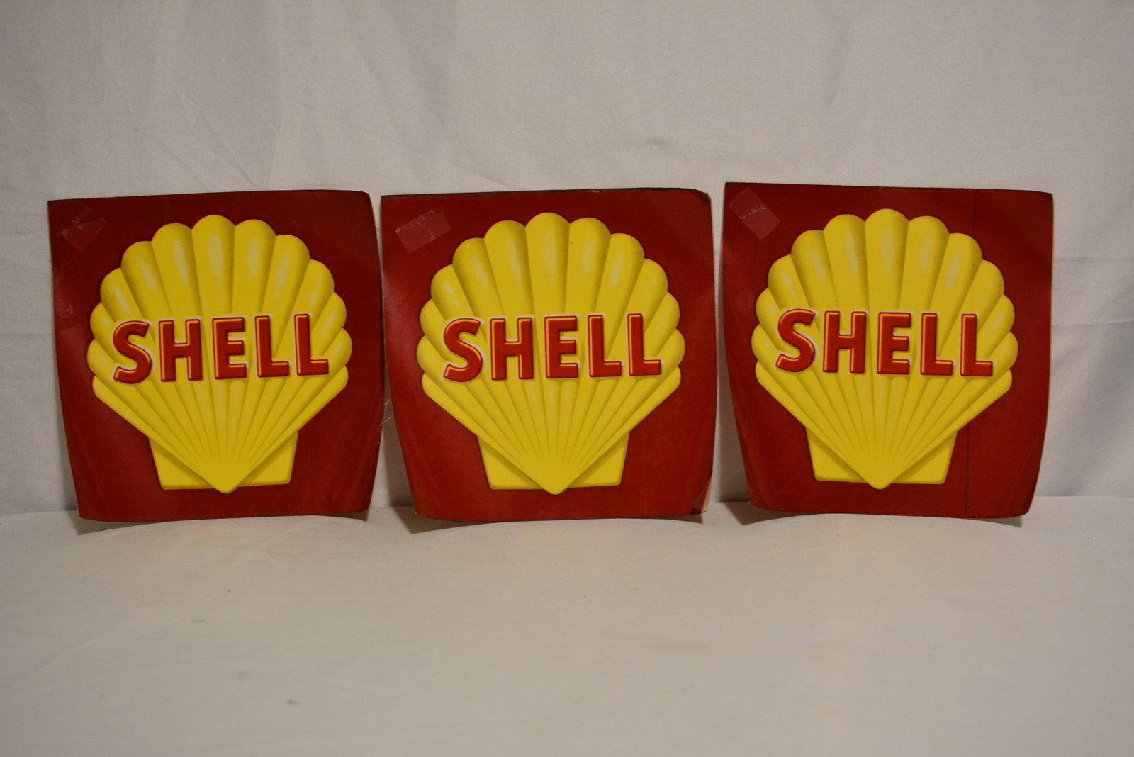 Set of Three Vintage Shell Gasoline Advertising Stickers: Set of three vintage Shell Oil gasoline advertising signs featuring the iconic raised yellow Shell emblem with red SHELL lettering against red backgrounds. Molded dimensional construction, with two ex