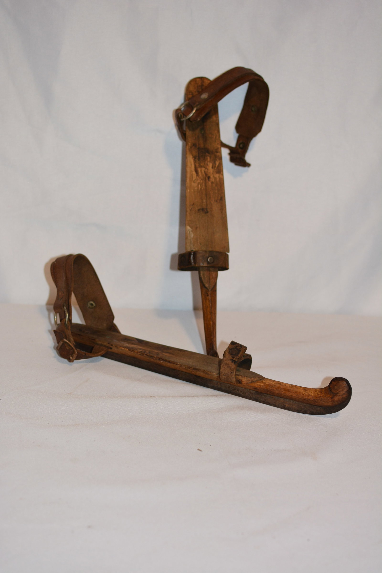 Pair of Antique Wooden Ice Skates with Leather Straps: Pair of early wooden ice skates featuring shaped hardwood foot platforms, upturned toes, iron runners, and leather ankle straps with metal buckles. Traditional construction typical of 19th-century to