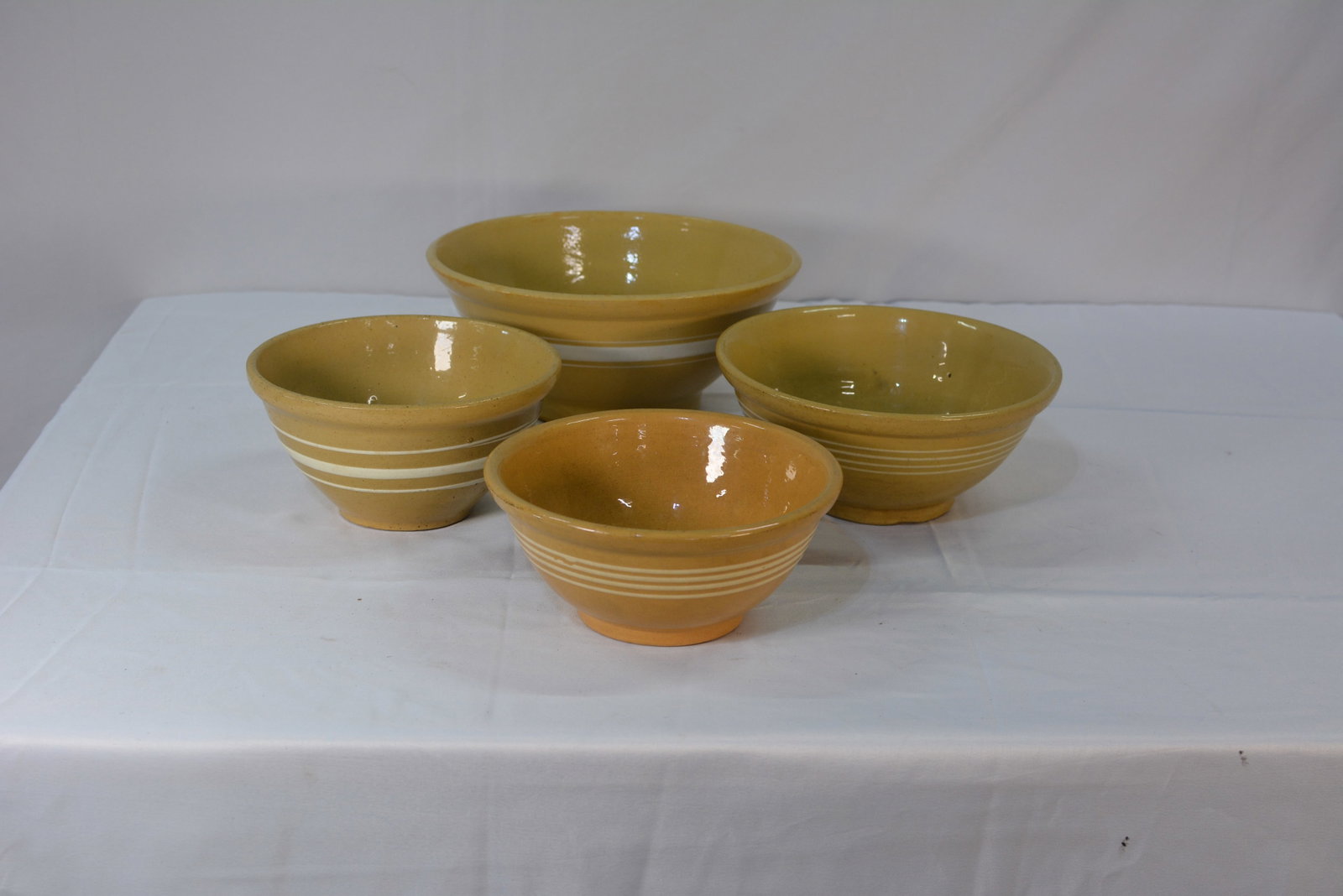 Yellow Banded Stoneware Mixing Bowls: Yellow stoneware mixing bowls featuring white banded detailing. These nesting bowls are designed for kitchen preparation and serving. the set includes various sizes with a glazed finish.