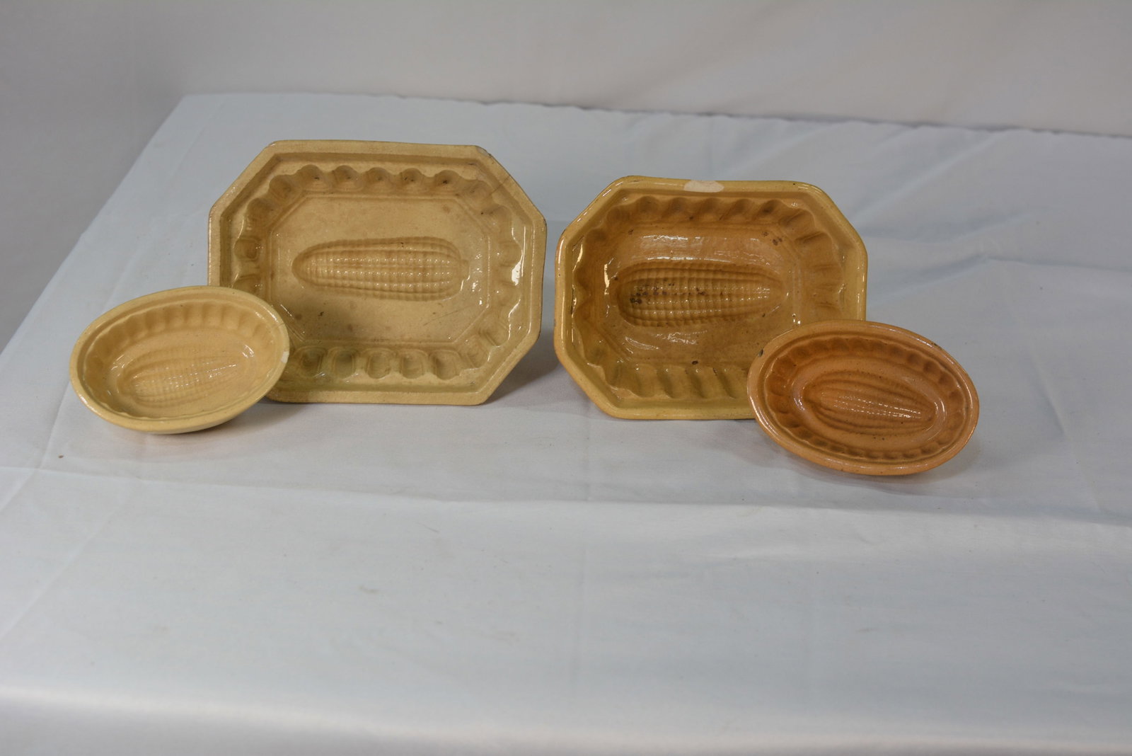 Yellow Glazed Earthenware Corn Molds: Yellow glazed earthenware kitchen molds featuring embossed corn motifs. the collection includes rectangular and oval shapes with fluted edges, suitable for decorative display or culinary use.
