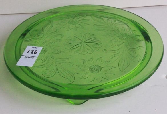 136. Antique green depression glass cake stand.: 3 footed - measures 10 inches in diameter.