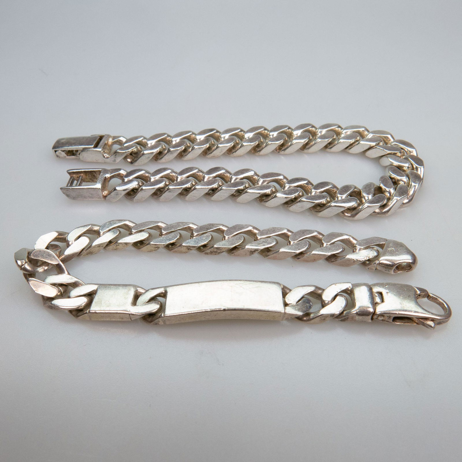 2 Italian Sterling Silver Curb Link Bracelets,: 2 ITALIAN STERLING SILVER CURB LINK BRACELETSincluding one with an ID panellength 9.0 in — 22.9 cm; length 8.0 in — 20.3 cm, 109.6 gramsEstimate: $100—150