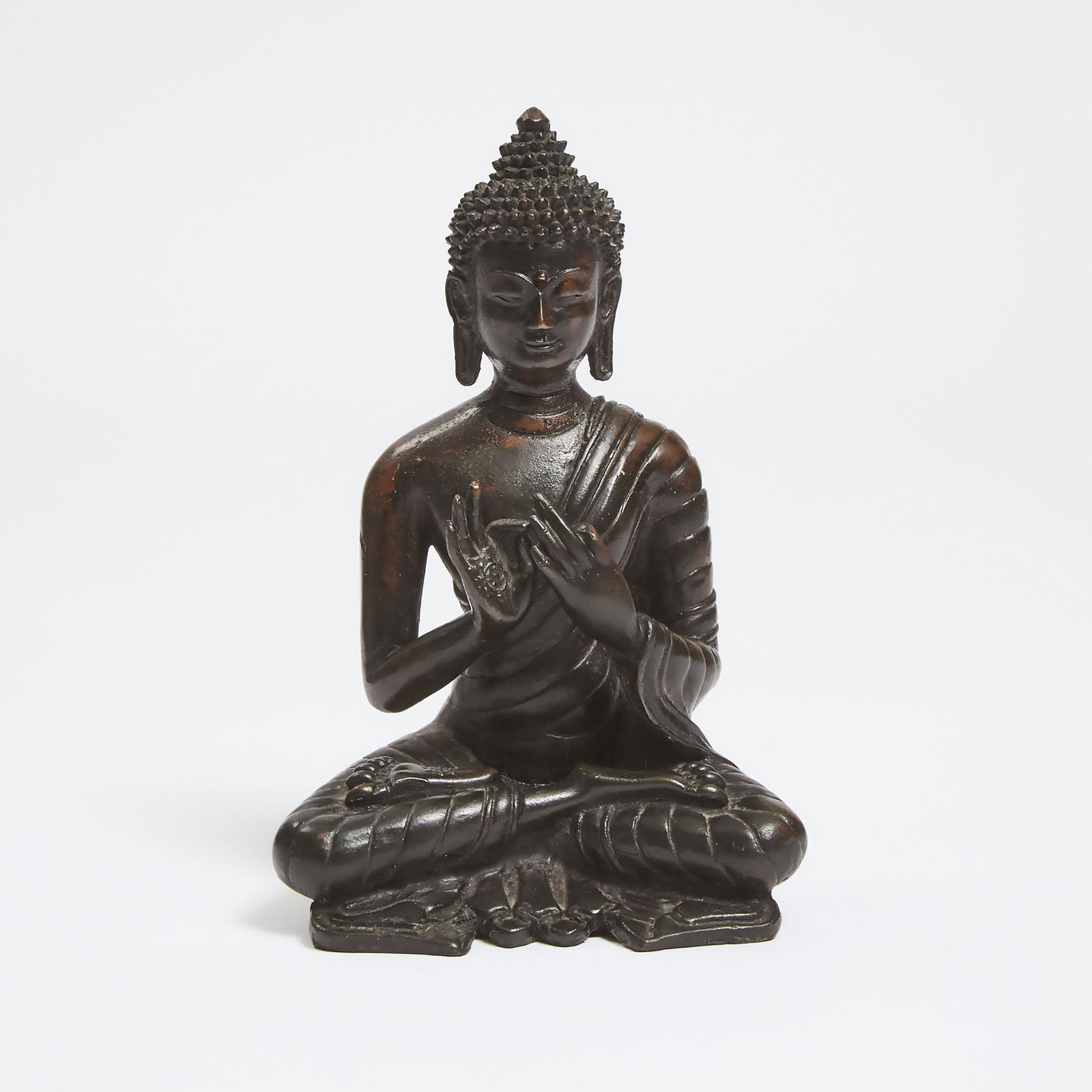 A Tibetan Bronze Seated Figure of Buddha, 18th Century or L: A Tibetan Bronze Seated Figure of Buddha, 18th Century or LaterThe hands in vitarka mudra; the paper and silk consecration intact, rolled and stored within, height 6.5 in — 16.5 cmEstimate: $400
