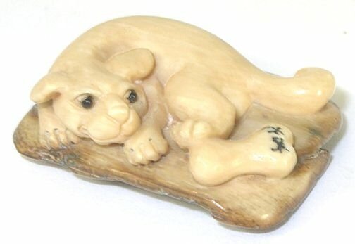 Dog with Bone Hand Carved Ivory Netsuke Figure: Hand Carved Ivory Netsuke Figure depicting a dog with a bone. Measures 1.25" L. Signed.