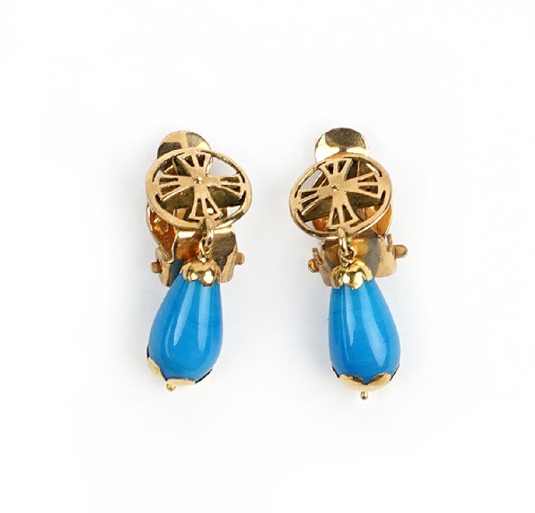 A Pair of 18 Karat Gold Earclips.: A Pair of 18 Karat Gold Earclips. Each cross form earclip has a blue bead suspended from it Wt: 5.5 grams