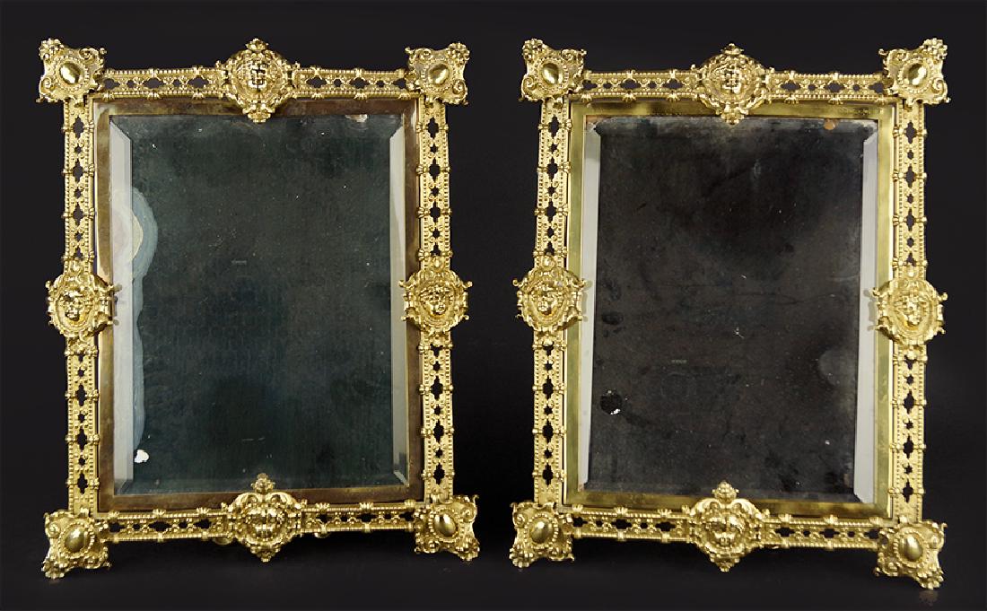 A Pair Of Brass Table Mirrors.: A Pair Of Brass Table Mirrors. Easel form brass table mirrors with cherubic decoration 18" x 14"