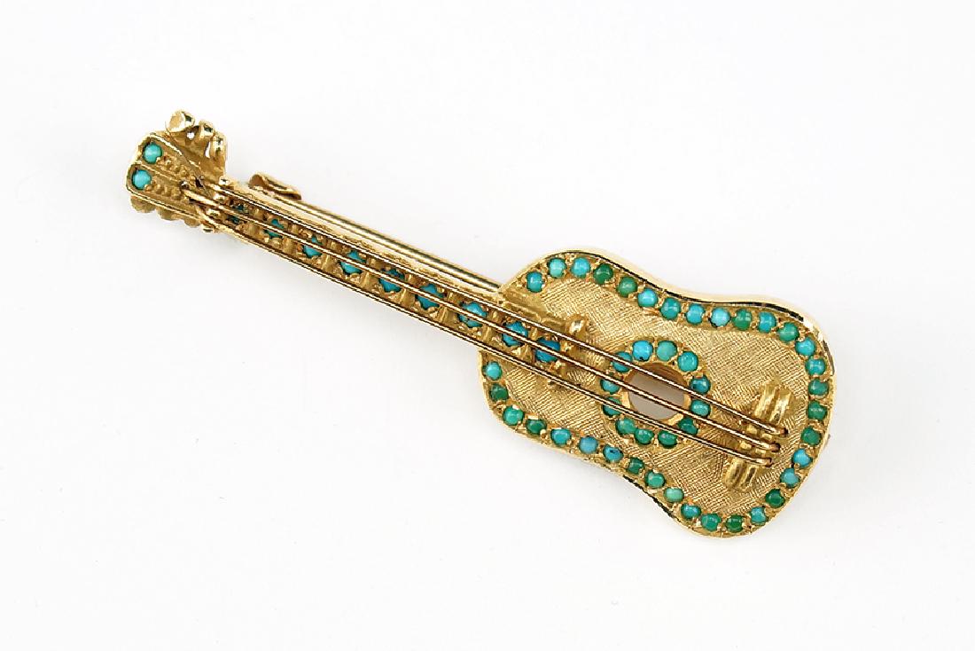 A 14 Karat Yellow Gold Brooch.: A 14 Karat Yellow Gold Brooch. Violin form brushed gold brooch studded with turquoise throughout Length: 1.75" Wt: 5.9 grams