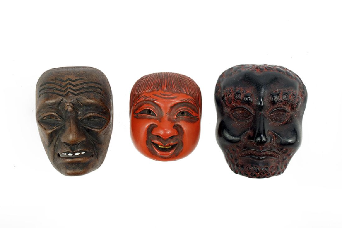 Three Mask Form Netsukes.: Three Mask Form Netsukes. Including Bizen pottery with white teeth signed 'Sekisen', one 19th century red lacquer signed 'Kajikawa', and one ebonized wood with curly hair, unsigned Pottery: 1 7/8" x 1