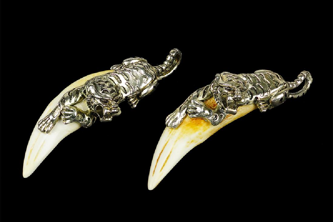 Two Tiger Teeth Pendants.: Two Tiger Teeth Pendants. Each tooth is mounted with a silvered metal reclining tiger Length: 5.25"