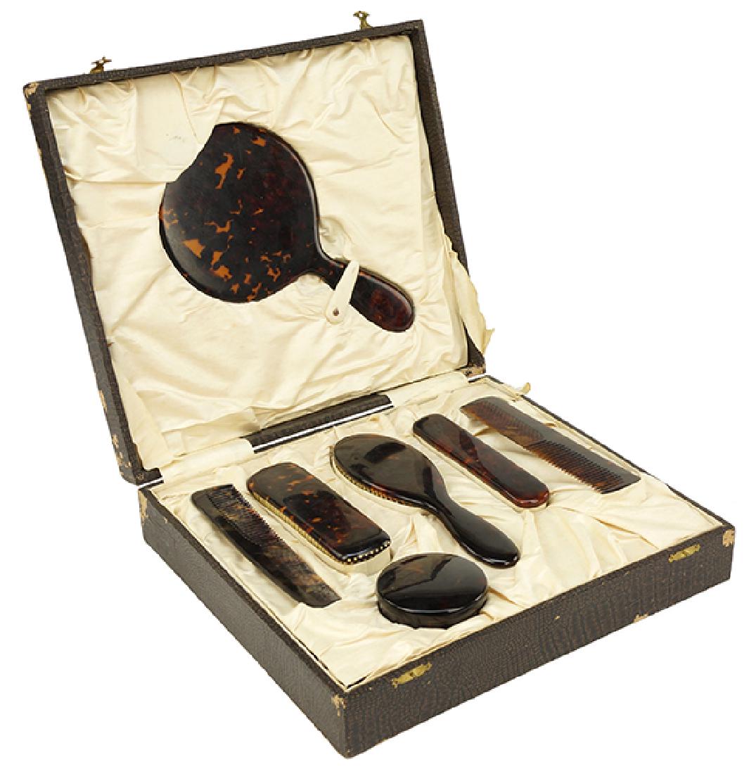 A Faux Tortoise Shell Vanity Suite.: A Faux Tortoise Shell Vanity Suite. Comprising a hand mirror, two hair combs, one hair brush, two clothing brushes and a vanity jar. Together with the original fitted case Case: 3" x 13.5" x 12.5"