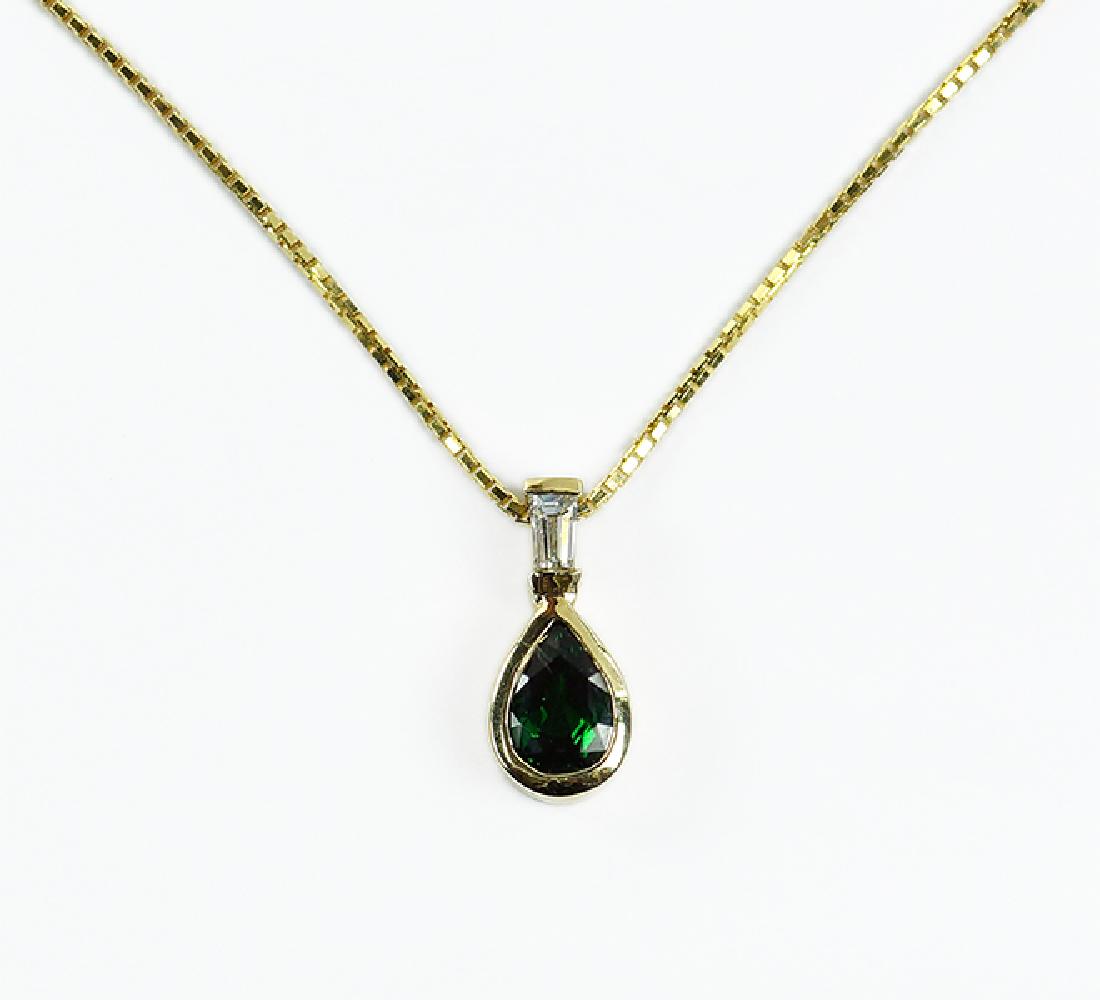 A Tsavorite Garnet & Diamond Pendant Necklace.: A Tsavorite Garnet & Diamond Pendant Necklace. 14 karat yellow gold pendant contains one pear shaped bezel set tsavorite garnet beneath one tapered baguette diamond. Together with a 14 karat box link