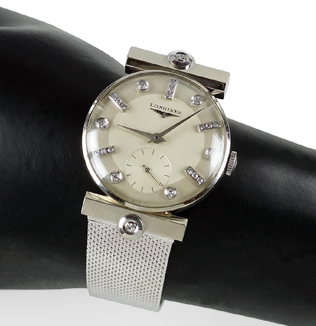 A Longines 14 Karat White Gold Watch.: A Longines 14 Karat White Gold Watch. White enamel and guilloche dial is mounted with 21 round diamonds. Two bezel set diamonds are mounted above and below the watch face. Mesh white gold bracelet and