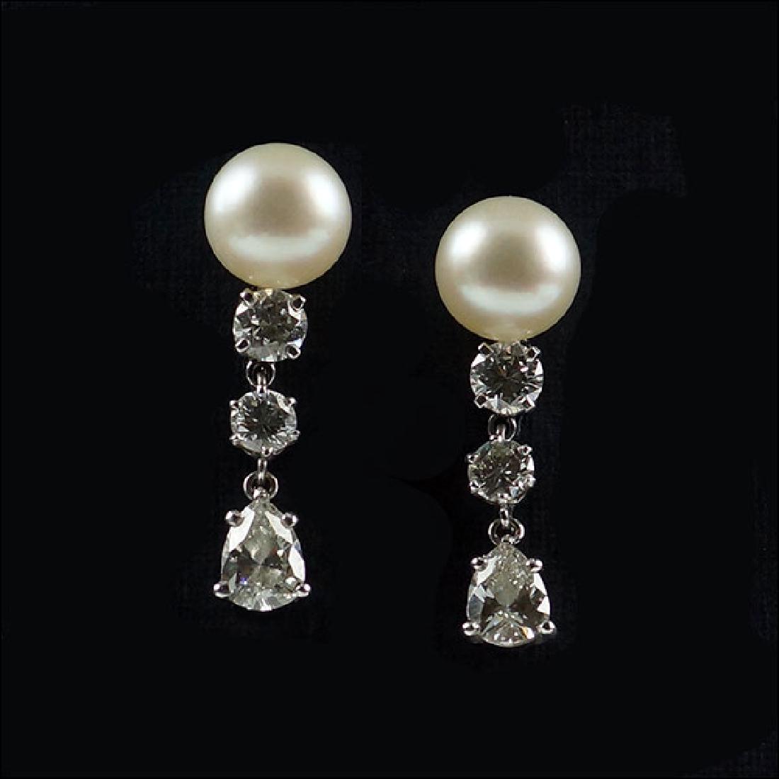 A Pair of Diamond & Pearl Earrings.: A Pair of Diamond & Pearl Earrings. 14 karat white gold screwback earrings are each mounted with one cream cultured pearl (8mm) with one prong set round brilliant diamond beneath which is approximatel