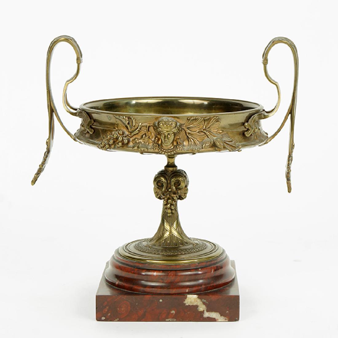 A Continental Tazza.: A Continental Tazza. Gilt bronze double handled tazza with Neo-Classical decoration and raised on a marble base 12.5" x 11.75"