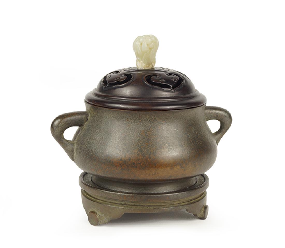 A Chinese Patinated Bronze Censer.: A Chinese Patinated Bronze Censer. Bearing a four-character mark on the underside. With a reticulated wood cover bearing a carved lingzhi form jade finial, double handles, and a patinated bronze stand