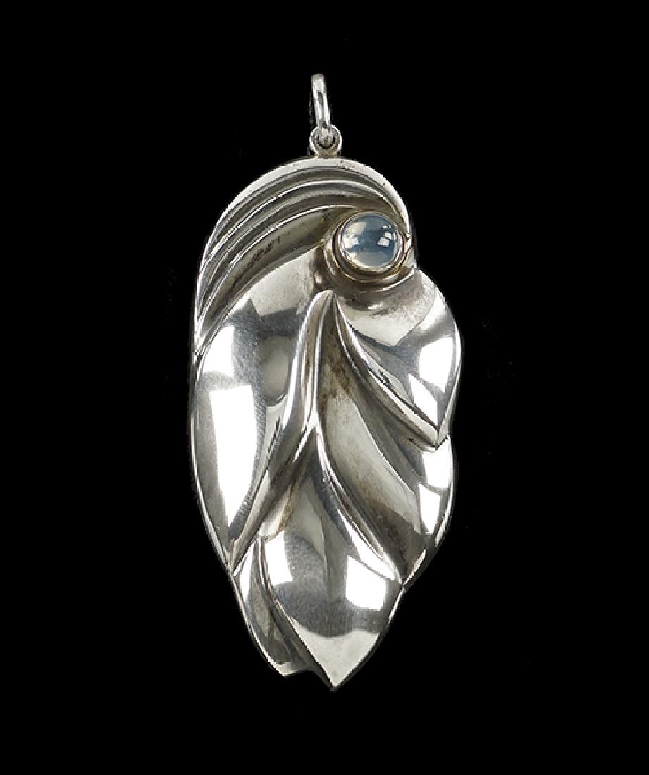 A Georg Jensen Pendant.: A Georg Jensen Pendant. Sterling silver leaf form brooch designed by Ole Kortzau contains one round moonstone cabochon. Reverse bears Jensen markings and "OK 360C" 2.5" x 1.25" Wt: 38.8 grams