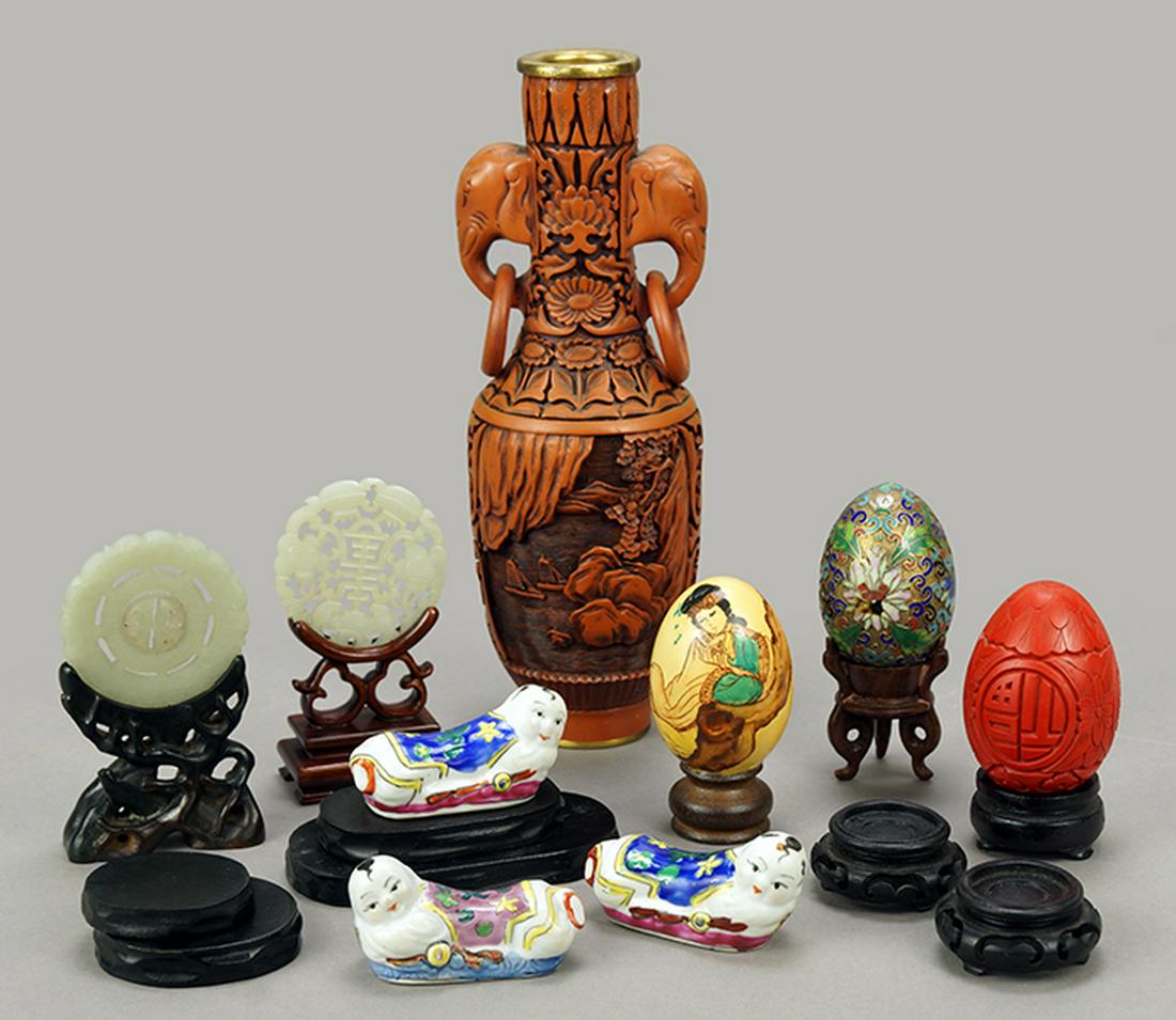Two Chinese Jade Bi Disks.: Two Chinese Jade Bi Disks. One fashioned as a pendant, both with fitted stands. Together with a collection of Asian decorative items including diminutive porcelain pillows, three eggs, and a lacquered