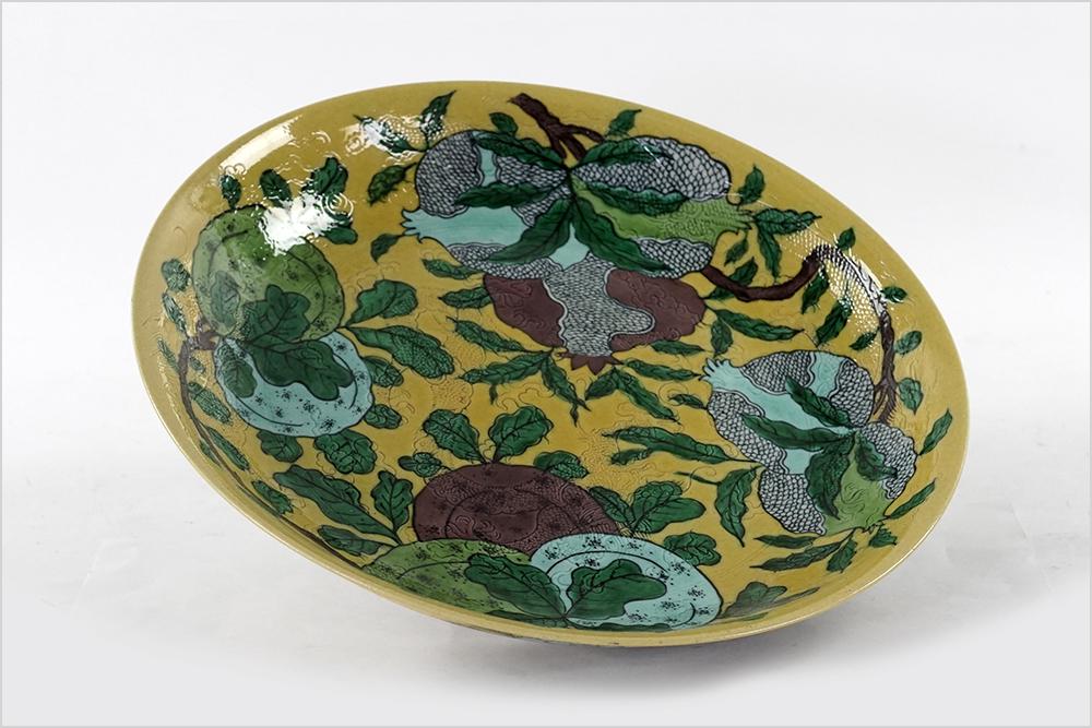 A Chinese Porcelain Pomegranate Charger.: A Chinese Porcelain Pomegranate Charger. Yellow ground charger decorated with pomegranates and an incised dragon motif, bearing an underglaze six-character Kangxi mark on the underside 2" x 12.25"