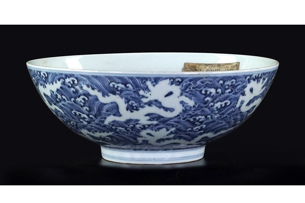 A Chinese Blue and White Porcelain Bowl.: A Chinese Blue and White Porcelain Bowl. The exterior having a decoration of waves and incised dragons, bearing an underglaze blue six-character Ming mark within double blue rings on the underside 3.7