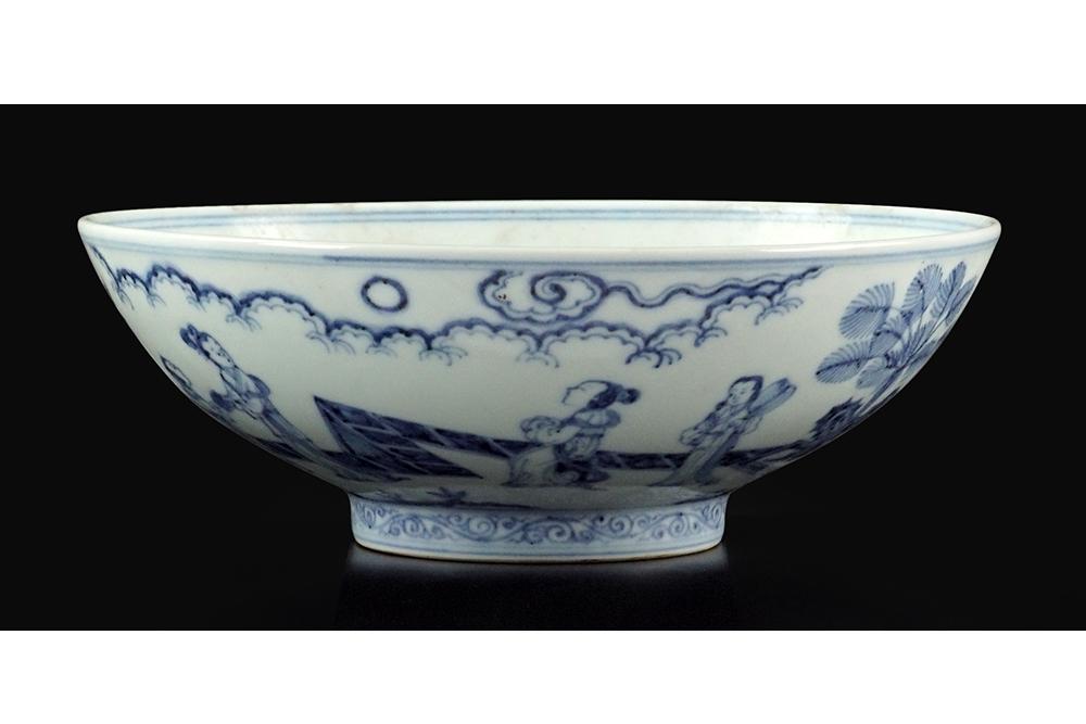 A Chinese Blue and White Porcelain Bowl.: A Chinese Blue and White Porcelain Bowl. Bearing a decoration of flowering trees to the bed and figures to the underside rim, with an underglaze six-character Ming mark within double blue rings on the