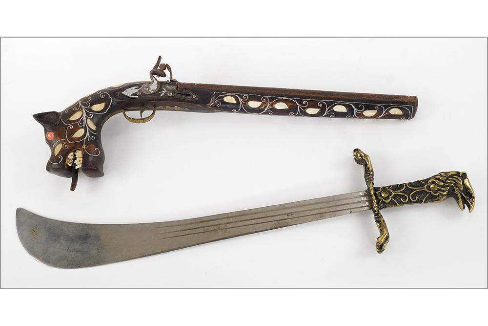 A Flintlock Pistol.: A Flintlock Pistol. With an animal form grip bearing animal teeth and abalone inlay throughout. Together with an English machete bearing a brass eagle form handle Length: 22.25"