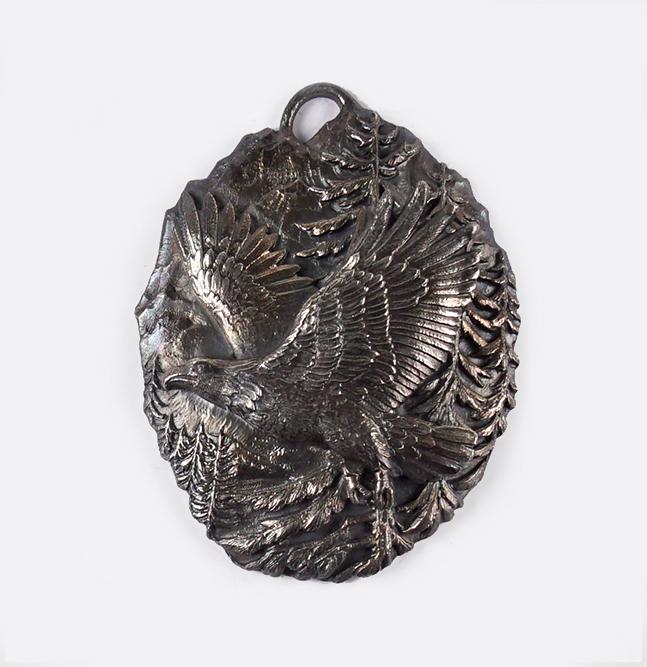 A Buccellati Sterling Silver Christmas Ornament.: A Buccellati Sterling Silver Christmas Ornament. Oval silver ornament depicting an eagle in flight against a forest backdrop 4.75" x 3.5" Wt: 2.45 ozt