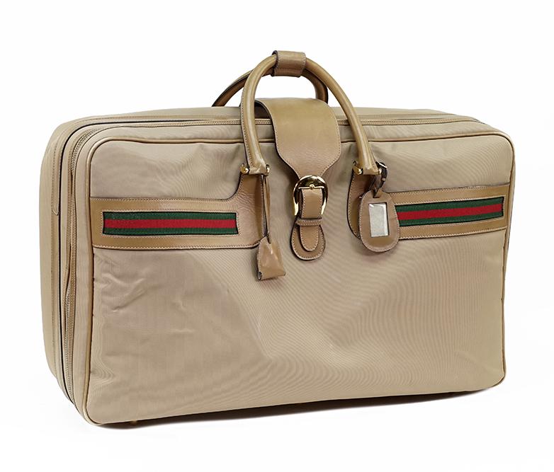 A Gucci Suitcase.: A Gucci Suitcase. Softsided treated canvas and leather suitcase with signature red and green ribbon stripe, Gucci lock, keys and pochette and luggage tag 17" x 26" x 9"